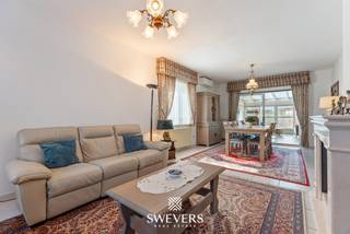 Voor meer info en foto’s, surf naar www.swevers.be – Deze ruime en instapklare bungalow aan de Barenbergseweg 118 in Diest combineert rustig wonen met veel praktische ruimte en extra mogelijkheden. De woning werd gebouwd in 1991, is zeer verzorgd en biedt 253m² bewoonbare oppervlakte op een perceel van 1.442 m² met aanpalende bouwgrond. Op het gelijkvloers vind je een centrale inkomhal met een gastentoilet, een ruime living van 34 m² met salon en eetkamer en een keuken van 15 m². Zowel de leefruimte als de keuken sluiten aan op het terras. Verder zijn er twee slaapkamers van ca. 16 en 15 m² en een badkamer, waardoor grotendeels gelijkvloers wonen perfect mogelijk is. De eerste verdieping omvat een derde slaapkamer van ca. 16 m² en een ruimte van ca. 24 m² die als vierde slaapkamer, bureau of hobbyruimte kan dienen. Twee zolderzones zorgen voor bijkomende bergruimte. Een grote troef is de volledige kelder van 106 m² met berging, wasplaats, provisieruimte en een parkeerkelder van ca. 42 m². De woning beschikt bovendien over zonnepanelen, een thuisbatterij en een goed E-peil. De aanpalende bouwgrond biedt extra mogelijkheden, bijvoorbeeld als ruime tuinzone of, mits de nodige vergunningen, voor een bijkomende woonoplossing. Winkels, scholen en ontspanning liggen op ca. 4 km, het openbaar vervoer op ca. 2,5 km en de snelweg op ca. 7,5 km. Voor meer informatie, bel 011 255 155. Bron bewoonbare oppervlakte: EPC – verslag.