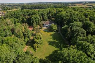<p>Tussen de glooiende velden van Boutersem, op een domein van maar liefst <strong>5,5 hectare</strong>, ligt een woning die zelden op de markt komt, en nog zeldzamer is in karakter: <strong>Huize Balder</strong>. Deze exclusieve villa combineert een rijke geschiedenis met een unieke architectuur en uitzonderlijke privacy. Het is een plek waar verleden en toekomst elkaar ontmoeten in een oase van rust, stijl en mogelijkheden.<br /><br /><strong>Huize Balder werd gebouwd in het interbellum door Alphonse Cappuyns</strong>, een briljante chemicus en pionier in de industriële productie van citroenzuur. Als oprichter van La Citrique Belge werkte Cappuyns nauw samen met Italiaanse partners – een band die zijn weerslag vond in de bouw van deze villa. <strong>Italiaanse (Siciliaanse) elementen zoals zuilengalerijen, arcades en mediterrane terrassen</strong> werden harmonieus geïntegreerd in een verder klassiek Belgische woningstijl. Het resultaat is een architecturaal geheel dat warmte, verfijning en wereldse allure uitstraalt.<br /><br />Met een <strong>bewoonbare oppervlakte van ca. 976 m²</strong> biedt de villa ruimte in overvloed. Er zijn <strong>10 slaapkamers</strong>, meerdere badkamers, een monumentale traphal met authentieke details en lichte leefruimtes met zicht op het parkdomein. Buiten vindt u een <strong>verwarmd zwembad</strong>, <strong>drie tennisvelden</strong> en meerdere terrassen die uitkijken op het omliggende groen. Alles is omgeven door een <strong>volledig afgeschermd domein</strong>, bereikbaar via een private oprijlaan, waardoor <strong>absolute privacy gegarandeerd is</strong>.<br /><br /><span>Ook qua ligging scoort deze eigendom uitzonderlijk goed.</span><span> Een </span><strong>strategische uitvalsbasis tussen Leuven en Tienen</strong><span>, met </span><strong>uitstekende verbindingen naar Brussel via de E40</strong><span><strong>.</strong> <br /><br /></span>Deze uitzonderlijke eigendom biedt <strong>veel meer dan alleen woonruimte</strong>. Dankzij haar schaal en indeling is Huize Balder perfect geschikt voor wie een <strong>familiedomein, praktijkruimte, retreatlocatie of zelfs een kleinschalige hospitality-ontwikkeling</strong> voor ogen heeft. Denk aan een exclusieve B&B, kunstenaarsresidentie, of een inspirerende thuis voor wie wonen en werken wil combineren. De mogelijkheden zijn legio, en de structuur van het pand leent zich uitstekend tot verdere verfijning.<br /><br />Maar Huize Balder is vooral ook een plek met een ziel. <strong>Een woning met een naam, een verhaal en een verleden.</strong> In de vorige eeuw fungeerde het domein als ontspanningsoord voor sportieve en culturele weekends. Kinderen speelden in de bossen, volwassenen genoten van rust, fitness en gezamenlijke diners op de terrassen. Vandaag is het tijd voor een nieuw hoofdstuk – geschreven door wie nu op zoek is naar iets écht bijzonders.<br /><br />Neem contact met ons op voor een bezoek of meer informatie. We laten u graag kennismaken met een plek die u nooit meer vergeet.<br /><br />AANDELENOVERDRACHT MOGELIJK!</p>