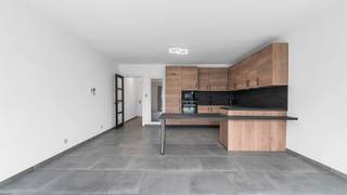 Aan de Staatsbaan 56 bus 1 in Neerharen (Lanaken) bevindt zich dit verzorgd en lichtrijk gelijkvloers appartement.<br />Het appartement geniet van een centrale en vlot bereikbare ligging aan de Staatsbaan in Neerharen. Winkels, scholen, openbaar vervoer en diverse dagelijkse voorzieningen bevinden zich in de onmiddellijke omgeving. Ook het centrum van Lanaken, Maastricht, Genk en Maasmechelen zijn vlot bereikbaar, waardoor deze locatie een ideale uitvalsbasis vormt voor wie rustig wil wonen en toch alles binnen handbereik wil hebben.<br /><br />Via de gemeenschappelijke inkomhal bereikt u het gelijkvloerse appartement aan de linkerzijde van het gebouw. De private inkomhal vormt het centrale verbindingspunt van het appartement en geeft toegang tot de verschillende leefruimtes.<br /><br />Vanuit de inkomhal komt u rechtstreeks in de mooie open keuken, die samen met de eetkamer en woonkamer één aangenaam geheel vormt. De keuken is praktisch ingericht en beschikt over voldoende werk- en opbergruimte. Dankzij de grote raampartijen geniet u vanuit zowel de keuken, de eetkamer als de woonkamer van een overvloed aan natuurlijk licht en heeft u vanuit elke ruimte een aangenaam contact met de buitenomgeving. De verbinding tussen de verschillende leefruimtes en de tuin zorgt voor een heerlijk open en ruimtelijk gevoel.<br /><br />Aan de achterzijde van de leefruimte bevindt zich de veranda, die een mooie overgang vormt naar de privatieve tuin. De veranda zorgt voor een aangename extra leefruimte en laat u volop genieten van het zicht en de verbinding met de tuin. De privatieve tuin biedt vervolgens een heerlijke plek om tot rust te komen, te genieten van het groen en op elk moment van de dag even naar buiten te gaan.<br /><br />Verder beschikt het appartement over twee volwaardige slaapkamers, waardoor er voldoende ruimte is voor een comfortabele hoofdslaapkamer, kinderkamer, bureau of hobbyruimte. Via de inkomhal bereikt u eveneens het aparte gastentoilet en een praktische berging.<br />Een absolute troef van dit appartement is de volledige onderkeldering. Het appartement beschikt over een volledig onderkelderd niveau, wat zorgt voor bijzonder veel extra bergruimte. Voorraad, hobbyspullen, seizoensgebonden spullen, materiaal of andere zaken die u liever netjes uit het zicht bewaart, kunnen hier gemakkelijk een plaats krijgen. Waar een appartement vaak genoegen moet nemen met een kleine berging, beschikt u hier over een volledige kelderverdieping. Extra ruimte die in het dagelijkse leven bijzonder handig is!<br /><br />Ook buiten heeft dit appartement heel wat te bieden. Naast de privatieve tuin beschikt u over een praktische tuinberging, ideaal voor tuinmateriaal en allerhande buitenspullen. Bovendien is er een privatieve autostaanplaats aanwezig, zodat u steeds over uw eigen parkeerplaats beschikt.<br /><br />Het appartement is voorzien van comfortabele en energiezuinige vloerverwarming, die zorgt voor een aangename en gelijkmatige warmteverdeling in de leefruimtes. Hierdoor geniet u het hele jaar door van een optimaal wooncomfort.<br /><br />Op energetisch vlak is dit appartement eveneens een echte uitschieter. Dankzij de aanwezige zonnepanelen en de energiezuinige eigenschappen van het appartement bedraagt het EPC slechts 37 kWh/m² per jaar en is er een E-peil van 18. Een bijzonder gunstige energiescore die een grote meerwaarde vormt voor het appartement. U woont hier niet alleen comfortabel, maar ook bijzonder energiezuinig, met een beperkte energievraag. In een tijd waarin energiezuinig wonen steeds belangrijker wordt, is dit dan ook een troef waar u op lange termijn volop van kunt genieten.<br /><br />Kortom, dit gelijkvloers appartement combineert een aangename open leefruimte met een mooie verbinding tussen binnen en buiten, een privatieve tuin met veranda, twee slaapkamers, een volledige kelder, tuinberging en eigen autostaanplaats. Voeg daar de zonnepanelen en het uitzonderlijk gunstige EPC van 37 kWh/m² per jaar aan toe en u krijgt een appartement dat niet alleen bijzonder praktisch en aangenaam woont, maar ook op energetisch vlak helemaal mee is.<br /><br />Bent u op zoek naar een verzorgd gelijkvloers appartement met ruimte, een eigen tuin en bijzonder veel extra bergruimte? Dan is dit appartement aan de Staatsbaan 56 bus 1 in Neerharen zeker een bezoek waard.<br /><br />STEDENBOUWKUNDIGE INFORMATIE:<br />- Stedenbouwkundige vergunning ontvangen: JA<br />- Stedenbouwkundige bestemming: Woongebied<br />- Verkavelingvergunning: NEEN<br />- Voorkooprecht RUP: NEEN<br />- Dagvaarding voor inbreuk op de stedenbouwkundige voorschriften: NEEN<br />- Overstromingsgevoeligheid<br />P-score: B<br />G-score: B<br />EPC: A label, 37 kWH/m²<br />Certificaatcode: 73107-G-OMV_2018144998/EP15119/A001/D01/SD017<br /><br />Wens jij dit appartement te bezichtigen? Aarzel niet en neem contact met ons op, we staan voor je klaar!<br />Tel.: 0032 497 84 48 80<br />E-mail: info@caenenvastgoed.be<br /><br />Tot binnenkort!<br />