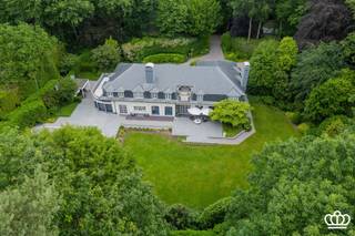 <p><span>Residentieel en discreet gelegen riante villa in Kapellenbos met o.a. diverse leef- en werkruimtes, 5 slaapkamers met elk een dressing, 3 badkamers, inpandige garage voor 2 wagens en voorzien van een lift. Omgeven door een mooi aangelegde en perfect onderhouden zuidwest gerichte tuin die veel zoninval en volledige privacy geniet.</span></p><p><span> </span></p><p><span>Gelijkvloers</span></p><p><span>Royale inkomhal met vide, vestiaire en gastentoilet. Via de inkomhal toegang tot de aparte bureauruimte met ingemaakte kasten.<br />Dubbele deuren leiden naar living met gezellig open haard en doorgang naar een tweede zit/eetkamer eveneens met open haard. Deze ruimtes genieten veel lichtinval vanwege de grote raampartijen en hebben een prachtig zicht op de tuin.</span></p><p><span>Grote en luxueuze keuken voorzien van alle hedendaagse inbouwapparatuur zoals 2 vaatwassers, 2 ovens, 2 micro’s, 2 vriezers, 2 koelkasten, een koele berging en aansluitend aan de keuken een lichtrijke veranda die is ingericht als eethoek.</span></p><p><span>Verder nog een praktische was en strijkkamer én een extra polyvalente ruimte dewelke kan ingericht worden als tweede bureau, speelkamer, fitness, …</span></p><p><span>Achter de veranda bevindt zich een sanitaire ruimte met douche, stoomcabine en toilet, ideaal te combineren met het zwembad.</span></p><p><span>Tot slot bevindt zich op het gelijkvloers nog een dubbele inpandige garage met automatische garagepoort. Verder biedt de ruime oprit veel parkeergelegenheid.</span></p><p><span> </span></p><p><span>Eerste verdieping</span></p><p><span>De eerste verdieping is bereikbaar via trap én lift.<br />Hier bevindt zich de mastersuite met zithoek, luxebadkamer en twee ruime dressings.<br />Verder zijn er nog vier slaapkamers met ingebouwde kasten en per twee slaapkamers, gedeelde badkamers.</span></p><p><span> </span></p><p><span>Zolder</span></p><p><span>Via een vlizotrap in de nachthal toegang tot de grote bergzolder.</span></p><p><span> </span></p><p><span>Kelder</span></p><p><span>De kelder is onderverdeeld in een technische ruimte en een wijnkelder. Verder kruipkelder.</span></p><p><span> </span></p><p><span>Tuin</span></p><p><span>De uitstekend onderhouden zuidwestgerichte tuin garandeert zon, rust en privacy, met aangelegde terrassen in blauwe steen en elektrische zonneluifels.</span></p><p><span>Het zwembad is momenteel gedempt en fungeert als oppompbaar regenwaterreservoir – maar kan terug in gebruik worden genomen.</span></p><p><span> </span></p><p><span>Bijzonderheden</span></p><p><span>-De villa is uitgerust met alle luxe en comfort zoals o.a. een lift, uitgebreid beveiligingssysteem, centraal stofzuigsysteem, waterontharder, irrigatie, buitenverlichting, etc.</span></p><p><span>-Onder het zwevend gelegde tapijt ligt in de leefruimtes een afzelia parket, in de hal en gang marmer.</span></p><p><span>-Energiezuinig door ondermeer gebruik van 8 warmtepompen, CV op gas middels 2 cascade geschakelde HR condensatie ketels, extra geïsoleerde spouwmuren, etc.</span></p><p><span>-De hoge plafonds (3.15m), de dubbele binnendeuren, grote ruimtes en veelheid aan ramen bieden een zeer royale beleving van de villa.</span></p><p><span>-Gelegen in Kapellenbos en nabij het centrum van Heide Kalmthout met winkels scholen en openbaar vervoer (treinstation)</span></p><p><span> </span></p><p><span> </span></p><p><span> </span></p>