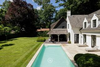 Située dans le prestigieux et verdoyant Sint-Martens-Latem, cette magnifique villa entièrement prête à l'emploi se trouve sur un magnifique terrain de 2 178 m². La propriété combine des espaces de vie généreux, une finition de haute qualité et un confort contemporain avec un emplacement exceptionnel et un jardin entièrement aménagé avec piscine.<br /><br />La villa comprend notamment:<br />Rez-de-chaussée<br />• Grand hall d'entrée avec vestiaire et toilettes invités<br />• Cuisine entièrement équipée avec des appareils Gaggenau de haute qualité, une chambre froide et une buanderie / bar à café attenante<br />• Salle à manger adjacente de taille normale avec une vue magnifique sur le jardin et un accès direct à la terrasse couverte<br />• Bureau spacieux, idéal pour le travail à domicile ou comme espace de travail séparé<br />• Salon chaleureux et spacieux avec cheminée, donnant sur le jardin magnifiquement aménagé<br /><br />Premier étage<br />• Grande chambre principale avec dressing sur mesure<br />• Salle de bains luxueuse avec sauna<br />• Trois chambres supplémentaires, chacune avec sa propre salle de bains attenante<br />• Buanderie spacieuse et pratique<br /><br />Expérience en plein air:<br />Le jardin entièrement aménagé avec terrasse couverte est un havre de paix et d'intimité. La piscine avec salle de bain attenante offre une expérience de vie et de détente exceptionnelle.<br /><br />Cave & espace de rangement<br />La maison dispose également d'une cave spacieuse avec cave à vin et espace de rangement supplémentaire.<br /><br />Garage & parking<br />Le garage intégré peut accueillir deux voitures et, si nécessaire, peut également être aménagé en espace de bureau ou polyvalent grâce au chauffage disponible. De plus, la villa dispose d'une grande allée avec un parking pour plusieurs voitures.<br /><br />Une maison exceptionnelle pour ceux qui recherchent de l'espace, du confort, de l'intimité et une finition de haute qualité dans un emplacement recherché.