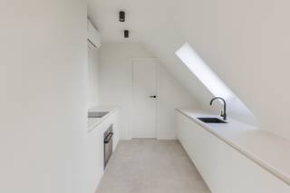 In het hart van het charmante Zeveneken, aan Hoekstraat 1, komt zelden zo'n kans voorbij. In een kleinschalig en kwalitatief project wordt dit prachtig afgewerkte dakappartement op de derde verdieping te koop aangeboden. Elk detail ademt klasse, comfort en verfijning. Wie hier binnenstapt, voelt het meteen: dit is thuiskomen.<br />De inkomhal leidt je naar de verschillende ruimtes, elk met hun eigen karakter. Via een elegante stalen deur kom je in de lichtrijke leefruimte op de hoek van het gebouw, waar een groot schuifraam zorgt voor overvloedig daglicht. Van hieruit heb je toegang tot het ruime terras – een heerlijke plek om buiten te genieten van het open zicht op de winkels en het kerkje van Zeveneken.<br />De open keuken vormt het hart van de leefruimte: stijlvol en praktisch tegelijk. Ze is uitgerust met een combi-oven, microgolf, vaatwasser en voldoende werkruimte om met plezier te koken. Aansluitend bevindt zich een handige berging, perfect voor extra opslag.<br />De stijlvolle badkamer is een oase van rust, voorzien van een moderne inloopdouche, een elegant lavabomeubel en een toilet. Daarnaast zijn er twee gezellige slaapkamers, ideaal als master bedroom en logeerkamer of bureau. Moderne technieken, zoals verwarming én koeling via een energiezuinige warmtepomp, zorgen voor optimaal wooncomfort.<br />Met een EPC-label A, een blanco elektriciteitsattest en hoogwaardige materialen is dit appartement niet alleen een ideale woonst, maar ook een goede investering. Op het gelijkvloers is er een gemeenschappelijke vuilnisberging en een afgesloten fietsenstalling. Recht tegenover het gebouw zijn er openbare parkeerplaatsen, en bovendien is er de mogelijkheid om een garage te huren of aan te kopen.<br />De ligging is perfect: op wandelafstand van winkels, apotheek, school en horeca, en uiterst centraal tussen Gent en Antwerpen, vlak bij de oprit van de E17.<br />Een stijlvol appartement, een doordacht ontwerp en een toplocatie – dit is wonen met klasse in Zeveneken.<br />Interesse? Neem vandaag nog contact op voor een bezoek en ontdek het zelf. Gsm 0496 299200.