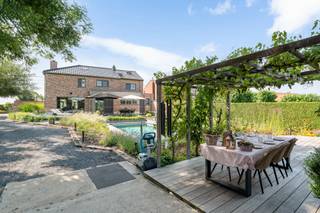 <p>Deze karaktervolle woning met praktijkruimte, gelegen op een perceel van 1.643m² kenmerkt zich door zijn unieke en rustige ligging. De woning werd volledig gerenoveerd in 2014 en is afgewerkt met hoogwaardige en kwaliteitsvolle materialen. In deze woning wordt met veel liefde geleefd, en dat voel je!<br /><br />Je betreedt deze woning via de ruime inkomhal met apart gastentoilet en toegang tot de praktijkruimte/bureau. Via een aparte trap is het mogelijk een extra (praktijk)ruimte op het eerste verdiep te bereiken.<br />Vanuit de inkomhal heb je tevens toegang tot het privé gedeelte van de woning bestaande uit een hall met toegang tot de vestiaire en douchekamer met toilet. Verder bevindt er zich een lichtrijke leefruimte met gebeitst parket en een hoogwaardig afgewerkte keuken met zicht op de tuin. Vanuit de keuken verkrijg je toegang tot een ruime bergruimte en wasplaats.<br />Op het eerste verdiep bevinden zich drie volwaardige slaapkamers, een dressing, apart toilet en badkamer met douche, bad, en badkamermeubel. Dit verdiep kan bereikt worden via een aparte privé – trap zodat je het praktijkgedeelte niet hoeft te storen. Op het zolderverdiep, toegankelijk via een vaste trap bevindt zich nog een extra slaapkamer. Via een zolderluik met uitklaptrap wordt er nog een extra zolderberging bereikt. In de tuin met uitzicht op het groen is het puur genieten en thuiskomen. Hier bevindt zich een luxueus zwembad, buitendouche, diverse (zon)terrassen en een ruime garage met extra werk – of ontspanningsruimte.</p>
<p><br />Leuk weetje: indien je geen praktijk of extra bureauruimte nodig hebt kan je deze ruimtes makkelijk inrichten als extra slaap – logeer – of hobbyruimte!</p>
<p><br /><strong>De woning is beschikbaar uiterlijk 31 december 2026.</strong></p>
<p><br />Ben je overtuigd en wens je deze woning te bezichtigen? Contacteer ons voor een bezoek via 015 68 26 08 of info@imperiavastgoed.be</p>