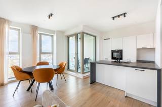 Schitterend appartement met panoramisch zicht op het Eilandje en Kempischdok.<br /><br />Gelegen op de achtste verdieping van de gloednieuwe residentie 'Doktoren' kijkt dit appartement uit over de Stad. <br /><br />U betreedt dit lichtrijke hoekappartement via de inkomhal met apart toilet. De ruime leefruimte biedt een panoramisch zicht over het Eilandje en de jachthaven. De open keuken is voorzien van alle comfort en gebruikelijke toestellen. De twee terrassen zijn rechtstreeks toegankelijk via de woonruimte.<br />De nachthal leidt u naar de masterslaapkamer met dressingmogelijkheid en douchekamer. Verder beschikt het appartement over twee slaapkamers en een separate badkamer met bad, toilet en wastafel.<br /><br />Een autostaanplaats dient verplicht bij gehuurd te worden aan 100 EUR/maand. <br /><br />Bijzonderheden: <br />- Kan gehuurd worden op vennootschap <br />- Recent appartement<br />- Mooie vergezichten over de Stad, Eilandje en de Jachthaven<br />- Bakkerij, slagerij, supermarkt en HoReCa in de directe nabijheid<br />- Ruim gemeenschappelijk dakterras op de 23e verdieping waar men gebruik van kan maken.
