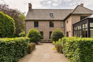 Een tijdloze villa in Genk, verscholen in het groen op een omheind perceel van 42 are. Achter de karaktervolle gevel in Vlaams kruisverband ontvouwt zich een ruime woonbeleving met warme materialen, parket, open haard en een orangerie met gashaard die het licht rijkelijk binnenbrengt.<br /><br />Met 4 slaapkamers, 2 badkamers en een afzonderlijk praktijkgedeelte met eigen inkom leent de woning zich zowel voor wonen als werken. De discrete ligging, verwarmde privé-oprit en vlotte verbinding naar het ZOL en de E314 brengen rust, privacy en bereikbaarheid samen.