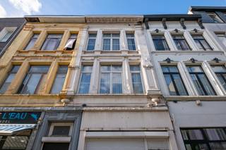 <p>Aan de Handelstraat 85, een winkelstraat in de wijk Stuivenberg, staat dit handelspand met woonst en achterbouw, opgetrokken omstreeks 1910 à 1920. Het ligt op een perceel van 146 m² met een gevelbreedte van ongeveer 5,1 m en een diepte van ongeveer 28,4 m, en heeft een totale nuttige oppervlakte van ongeveer 451 m². Winkels, scholen en ziekenhuizen liggen in de buurt, er zijn verschillende tram- en bushaltes binnen een straal van 1 km en de op- en afrit Borgerhout van de R1 ligt op ongeveer 2,4 km. Het pand is minder goed onderhouden en een grondige renovatie is aangewezen, maar het biedt veel ruimte en heeft nog heel wat authentiek karakter.<br /><br />Indeling<br />Aan de straatkant zijn er een rolluik voor de handelsruimte. Het gelijkvloers deed dienst als restaurant: een diepe ruimte met linoleumvloer, zichtbare houten balkjes aan het plafond en een trap naar de verdieping. Daarachter liggen de bediening, de keuken met eenvoudige industriële uitrusting, een wasplaats, twee toiletten, een hal en een bergplaats.<br />Op de eerste verdieping vooraan liggen de living en de eetkamer, met stucwerk aan het plafond en een schouw met kachel. Verder is er een eenvoudige keuken met stenen aanrecht met twee bekkens en een badkamer met bad, twee lavabo's, toilet en elektrische boiler, beide met een granito vloer.<br />De tweede verdieping telt twee slaapkamers, elk met een schouw. Op de zolderverdieping vooraan liggen nog twee kamers met dakvensters. Doorheen het pand vind je authentieke elementen zoals marmeren schouwen, een trap met gedraaide balusters en een binnendeur met geëtst glas.<br />De achterbouw heeft op de eerste verdieping en op de zolderverdieping telkens een hal, een voorkamer en een achterkamer met houten vloer. Hij is slecht onderhouden en heeft geen comfort: de vloerplaat van het gelijkvloers is ingezakt en moet vervangen worden.<br />Vooraan is het pand onderkelderd, met onder meer een stookkelder, mazoutkelder en bergkelder. Ook onder de achterbouw zijn er kelders, die momenteel niet toegankelijk zijn.<br /><br />Buiten<br />Achteraan is er een verharde koer, noord georiënteerd, met toegang tot een overbouwde doorgang naar de straat. Het perceel is deels bezwaard met een recht van doorgang en heeft zelf een recht van doorgang via die gang naar de achterbouw.<br /><br />Technisch<br />Centrale verwarming op mazout, met tank en ketel in de kelder vooraan. Het schrijnwerk is deels PVC met isolerend glas en deels ouder met enkel glas. Volgens het EPC zijn het hellende en het platte dak niet geïsoleerd.<br /><br />Troeven: handelsgelijkvloers met aparte inkom, 146 m² grond, ongeveer 451 m² nuttige oppervlakte, woonst met 2 slaapkamers en 2 zolderkamers, achterbouw met 4 bijkomende kamers, authentieke elementen.<br /><br />EPC: 682 kWh/m².jaar, label F, UC 20260915-0003951521-RES-1<br />Stedenbouwkundige info: stedenbouwkundige vergunning van 29/10/1965, gewestplan woongebied, gemeentelijk RUP 2060 (zone voor detailhandel), geen verkavelingsvergunning, voorkooprecht RUP 2060.<br />Overstromingsgevoeligheid: P-score A, G-score A.<br />Asbestattest: attestnummer 20260921-000087.000 van 21 september 2026, conclusie niet-asbestveilig.<br /><br />Interesse? Contacteer ons voor een bezoek.</p>