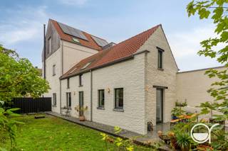 Achter de gevel van deze charmante woning schuilt een bijzonder smaakvol gerenoveerd interieur waarin karaktervolle elementen en hoogwaardige materialen harmonieus samenkomen. Hier werd gekozen voor duurzame materialen, authentieke accenten en een afwerking met oog voor detail. De benaming 'stadshoeve' vat het geheel mooi samen. Met het openbaar vervoer (tram) of fiets is het centrum van Gent slechts 15 minuten. De woning ligt op het einde van een doodlopende straat, er is hier dus geen doorgaand verkeer.<br />Via de inkomhal betreedt u de woning, waar de ruime leefruimte meteen een aangenaam gevoel van ruimte en karakter uitstraalt. De recente houtkachel zorgt er voor extra gezelligheid en vormt de ideale plek om tijdens de koudere maanden heerlijk tot rust te komen. Centraal in de woning bevindt zich de prachtige stalen trap, die als architecturale eyecatcher de verschillende verdiepingen met elkaar verbindt en het interieur een uitgesproken, eigentijdse uitstraling geeft.<br />Achteraan bevindt zich de grote en stijlvolle keuken, waar het arduinen werkblad, de authentieke tegelvloer en een karaktervol Smeg-fornuis zorgen voor een geslaagde combinatie van esthetiek en functionaliteit. De natuurlijke bakstenen muren, houten ramen en authentieke, eerlijke materialen geven de woning een warme, tijdloze uitstraling. Verder zijn er op het gelijkvloers een apart gastentoilet, een douche en een praktische bijkeuken met aansluitingen voor een wasmachine en droogkast. Zowel hier als in de keuken is er een mooi zicht op de groene tuin.<br />Op de eerste verdieping bevindt zich een tweede zithoek, ideaal als extra leefruimte, leeshoek of ontspanningsplek. Daarnaast zijn er drie kamers, waarvan één vooraan en twee achteraan. Afhankelijk van uw noden kunnen deze worden ingericht als slaapkamers, dressing of bureau. De badkamer is bijzonder verzorgd afgewerkt en beschikt over een douche met verfijnde mozaïek, een ligbad, een dubbele lavabo en een toilet.<br />De tweede verdieping is volledig gewijd aan de ruime masterbedroom, een heerlijke plek om in alle rust tot de dag te komen of af te sluiten.<br />Ook buiten heeft deze woning heel wat te bieden. Het grote, windbeschutte terras vormt de ideale plek om gezellig te tafelen en lange zomeravonden door te brengen in volledige privacy. De muren van het terras deden dienst als stallen van een koetsiershuis. Deze dragen opnieuw bij aan de authenticiteit van de eigendom. Aansluitend ligt de ruime en volledig omheinde tuin, met achteraan een groot tuinhuis dat tal van praktische opbergmogelijkheden biedt. De zij- en achtergevel werden bovendien recent volledig opnieuw gekaleid, wat bijdraagt aan de verzorgde uitstraling van de woning. Een oprit (met voorziening voor laadpaal) met plaats voor één wagen maakt het geheel compleet. De woning beschikt ook over zonnepanelen. <br />Wenst u deze prachtige woning te bezoeken of wenst u meer informatie? Contacteer Benjamin De Wit (0473 97 08 80 – benjamin@rosseel.be).