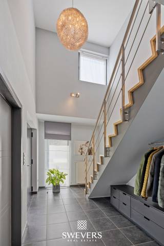 Voor meer info en foto’s, surf naar www.swevers.be – Deze instapklare open bebouwing aan de Schutenseweg 95 in Zonhoven biedt maar liefst 267 m² woonoppervlakte op een perceel van 10a54. De woning uit 2005 combineert ruimte, comfort en veelzijdigheid, ideaal voor grote gezinnen, zorgwoning of wie wonen en werken wil combineren.<br />Via de imposante inkomhal bereikt u de lichtrijke leefruimte van 41 m² met grote raampartijen en directe toegang tot de tuin. Aansluitend bevindt zich een afzonderlijk bureau dat eenvoudig opnieuw bij de woonkamer kan worden betrokken. De ruime leefkeuken van 22 m² beschikt over alle nodige inbouwtoestellen, veel bergruimte en plaats voor een grote eettafel. Verder zijn er op het gelijkvloers een wasplaats met maatkasten, een extra douche en een praktische vestiaire. Een grote troef is de voormalige inpandige garage die werd ingericht als praktijk- of hobbyruimte van circa 34 m² met eigen ingang. Deze ruimte biedt tal van mogelijkheden als kantoor, atelier, zorgunit of logeerverblijf. Op de verdieping bevinden zich vier slaapkamers, waaronder een masterbedroom met his-and-her inloopdressing. De vernieuwde badkamer is uitgerust met een ruime dubbele inloopdouche, dubbele lavabo en maatkasten. Daarnaast is er een afzonderlijk toilet aanwezig. De woning is volledig onderkelderd met ongeveer 60 m² extra bergruimte en beschikt bovendien over een zolder van circa 60 m² met uitbreidingsmogelijkheden. Buiten geniet u van een verzorgde tuin met terras, fruitbomen, bessenstruiken en fietsenstalling. Extra comfort wordt geboden door airco’s, zonnepanelen met thuisbatterij en een laadpaal voor elektrische voertuigen. De rustige ligging combineert een vlotte bereikbaarheid met scholen, openbaar vervoer, winkels, Hasselt en de autosnelweg in de nabije omgeving. Voor meer informatie, bel 011 255 155. Bron bewoonbare oppervlakte: EPC – verslag.