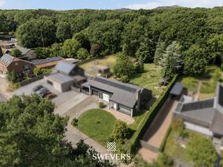 Voor meer info en foto’s, surf naar www.swevers.be – Ruimte, comfort en een groen uitzicht staan centraal in deze gelijkvloerse open bebouwing aan de Koerselsesteenweg 168 in Koersel. De woning werd gebouwd in 1973 en ligt op een uitzonderlijk perceel van 2.086 m². Met een bewoonbare oppervlakte van 339 m², vier slaapkamers en tal van extra ruimtes is dit een ideale gezinswoning, maar ook bijzonder geschikt voor wie wonen en werken wil combineren. Een grote troef is de ruime zolder van maar liefst 186 m² met Veluxramen. Deze biedt mogelijkheden voor extra slaapkamers, hobbyruimte of speelkamer. Ook een verdere invulling in functie van kangoeroewonen behoort tot de mogelijkheden. Doorheen de jaren werden belangrijke renovaties uitgevoerd aan onder meer het dak, de ramen, verwarming, keuken en verwarmingsketel. Daarnaast beschikt de woning over zonnepanelen, airconditioning, een alarminstallatie, een regenwaterput van 10.000 liter en een driefasige elektriciteitsaansluiting. De lichtrijke living van 42 m² sluit aan op de vernieuwde keuken. Verder zijn er een badkamer, apart gastentoilet, een wasplaats en vier slaapkamers van 18 m², 17,5 m² en tweemaal 10,5 m². De slaapkamer aan de voorzijde kan perfect ingericht worden als bureau of praktijkruimte. Ideaal voor zelfstandigen, mensen met een bijberoep of iemand die veel van thuis uit werkt. Extra troeven zijn de inpandige garage van 21 m², carport, een volledig onderkelderde verdieping van 177 m². De ruime tuin geniet van veel privacy en een prachtig groen uitzicht. Het perceel is volledig afgesloten, hetgeen ideaal is voor mensen met huisdieren. Winkels, scholen, restaurants en het centrum van Beringen liggen op ongeveer 1 km. Openbaar vervoer bevindt zich op amper 50 meter. Voor meer informatie, bel 011 255 155. Bron bewoonbare oppervlakte: EPC – verslag.