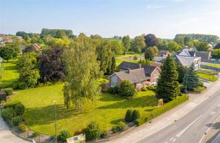 Karaktervolle ruime woning op een perceel van 23a 20 Deze klassevolle woning uit 1969 is gelegen op een prachtig perceel en biedt een uitstekende basis voor wie op zoek is naar ruimte, comfort en tal van mogelijkheden. De woning dient opgefrist te worden, maar beschikt over een solide structuur en een doordachte indeling. Bij het betreden van de woning valt meteen het ruime karakter op. De woning beschikt over een grote living van 56m², keuken en drie volwaardige slaapkamers en een apart bureau, gelegen op een half niveau, wat zorgt voor een gezellige en functionele indeling. Verder zijn er kelders, een kruipkelder en een grote inpandige garage voor 3 wagens, waardoor er volop bergruimte en praktische mogelijkheden aanwezig zijn. Een bijzonder pluspunt is de ruime tuin. De linker tuinzone bevindt zich nog in bouwzone, wat potentieel biedt voor het realiseren van een extra garage, carport of bijgebouw, onder voorbehoud van de geldende stedenbouwkundige voorschriften en vergunningen. Deze eigendom combineert een rustige ligging, een royaal perceel en tal van uitbreidingsmogelijkheden, waardoor ze uitermate geschikt is voor gezinnen of kandidaten die op zoek zijn naar een woning met toekomstpotentieel. EPC F 525 met renovatieverplichting. CV Stookolie, dubbele beglazing met rolluiken.