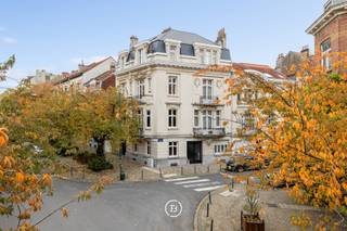 Tussen het Ambiorixplein en de levendige wijk rond Plasky, nabij Diamant en het Jubelpark, bevindt zich dit uitzonderlijke herenhuis met drie gevels, gebouwd in 1912 in verfijnde Beaux-Artsstijl. Met een bewoonbare oppervlakte van circa 631 m² op een perceel van 2a 20ca, biedt deze woning een unieke combinatie van elegantie, ruimte en authenticiteit.<br />Via de hoofdingang aan de prestigieuze Emile Maxlaan betreedt men een wereld van verfijnde architectuur en tijdloze charme. Tal van authentieke elementen werden zorgvuldig bewaard: originele parketvloeren, rijkversierde schouwmantels, fijn lijstwerk, glas-in-looddeuren, siersmeedwerk, fresco’s en ornamenten getuigen van een uitzonderlijk vakmanschap.<br />De prachtige leefruimtes worden gekenmerkt door hoge plafonds, royale volumes en veel natuurlijk licht, wat bijdraagt tot een gevoel van grandeur en harmonie. Deze eigendom leent zich uitstekend tot veelzijdig gebruik – als prestigieuze gezinswoning, kantoorruimte of representatief pand met gemengd karakter.<br /><br />Een pand vol geschiedenis en karakter, dat de grandeur van het begin van de 20e eeuw weerspiegelt en tal van mogelijkheden biedt in één van de meest charmante lanen van Schaarbeek, omgeven door elegante handelszaken, sfeervolle restaurants en uitstekende verbindingen.<br /><br />Indeling<br />Gelijkvloers: majestueuze inkomhal met monumentale trap, verfraaid met een fresco geïnspireerd op het Cauchiehuis, elegante ontvangstruimte met houtwerk en glas-in-loodramen, vestiaire en gastentoilet, volledig uitgeruste keuken met toegang tot terras en tuin, souplex (gelijkvloers + kelder).<br /><br />Eerste verdieping: ruim salon met hoge plafonds en moulures, grote eetkamer met authentieke details, tweede keuken met eetruimte en balkon<br /><br />Tweede verdieping: 3 ruime slaapkamers, dressing, grote badkamer met ligbad, douche en toilet<br /><br />Derde verdieping: 4 slaapkamers<br /><br />Zolderverdieping: volledig geïsoleerd dak vernieuwd in 2025. Mogelijkheid tot inrichting (extra kamers, enz.)<br /><br />Kelderverdieping: ruime kelders, wijnkelder, wasruimte en stookruimte met nieuwe condensatieketel op gas (2022).