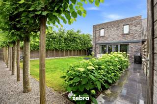 <strong>Het bezoekmoment gaat door op zaterdag 5 september 2026 (enkel op afspraak).</strong><br /><br />De woning (BJ 2015) combineert hedendaags wooncomfort met uitstekende energieprestaties dankzij vloerverwarming, een warmtepomp en zonnepanelen (11 stuks, 4785 Wp), goed voor een uitzonderlijk energiezuinig EPC-label A+. Verder beschikt de woning over diverse extra voorzieningen, waaronder domotica, een ventilatiesysteem D, een waterverzachter en een regenwaterput van 15.000 liter.<br /><br />Via de inkomhal met gastentoilet betreedt u de woning. De lichtrijke leefruimte met volledig uitgeruste open keuken vormt het hart van de woning.<br />De keuken werd afgewerkt met kwalitatieve materialen en is uitgerust met moderne toestellen, waaronder een inductiekookplaat met geïntegreerde afzuiging, twee combi-ovens, ... Aansluitend bevindt zich een praktische keukenberging.<br /><br />Op de eerste verdieping zijn er vier volwaardige slaapkamers (plat dak), allemaal voorzien van internet- en tv-aansluitingen. De ruime badkamer beschikt over een dubbele wastafel, ligbad en douche. Daarnaast is er een afzonderlijk toilet aanwezig.<br /><br />De zonnige, zuidwestgerichte tuin biedt een aangename buitenruimte en beschikt over een praktische uitweg naar de bijhorende garagebox, inbegrepen in de prijs. Verder zijn er een zonneluifel en een tuinhuis aanwezig. Via het poortje aan de rechterzijde van de woning is de tuin bovendien gemakkelijk bereikbaar.<br /><br /><strong>Ook wild geworden van deze thuis?<br />Twijfel niet langer en leg vandaag nog uw bezoek vast!</strong>