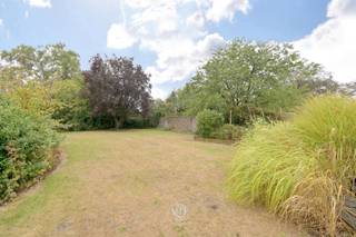 Achter deze karakteristieke voorgevel schuilt een ruime en praktische woning met een aangename tuin, gelegen op een mooie centrale locatie aan de kerk, in de recent heraangelegde en aantrekkelijke dorpskern.<br /><br />Bijzonder handig is de aanwezige ‘poort’, die zowel als inkom als garage kan fungeren. Voor de garage is bovendien een openbare parkeerplaats voorzien, die door de eigenaar gebruikt kan worden, aangezien deze zich voor de private garagepoort bevindt.<br /><br />Op het gelijkvloers bevinden zich een ruime leefruimte, een bureel dat eveneens als slaapkamer kan worden ingericht, een berging/wasplaats en een centraal gelegen keuken achteraan. Daarnaast beschikt de woning over een kelder en een veranda.<br /><br />De eerste verdieping omvat vier slaapkamers en een badkamer.<br /><br />Ook de zolderverdieping biedt dankzij de vaste trap en het ruime volume heel wat mogelijkheden en kan volledig naar eigen wens worden ingericht. Zo kunnen hier eventueel nog extra kamers of andere functionele ruimtes worden gecreëerd.<br /><br />Buiten zijn er nog enkele bijgebouwen aanwezig en de aangename tuin staat garant voor heerlijk vertoeven.<br /><br />Mits de nodige renovatiewerken maak je van deze woning een echte parel!