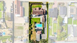 elegen op een royaal perceel van 2.229 m² combineert deze woning een praktische indeling met tal van mogelijkheden om er volledig uw eigen thuis van te maken. De gelijkvloerse verdieping werd volledig vernieuwd en straalt een eigentijdse, aangename sfeer uit. De ruime leefruimte en gezellige leefkeuken vormen het hart van de woning, met veel natuurlijke lichtinval en maatkasten die doorheen de woning zorgen voor extra comfort en opbergruimte.
<p>De volledig aangelegde tuin met grote terrassen en een verwarmd zwembad, biedt volop ruimte om te genieten van rust en privacy. Het poolhouse kan nog naar eigen smaak verder ingericht worden. De woning beschikt over een carport vlakbij de achterdeur en twee hogere carports achteraan, naast een ruime garage met automatische poort.</p>
<p>De rustige ligging is een extra troef, met winkels, scholen en belangrijke verbindingswegen in de nabije omgeving.</p>
<p>Beschikbaar uiterlijk eind augustus 2027.</p>
<p><strong>Troeven</strong>:</p>
<ul><li>Gunstig EPC B – 197 kWh/m²</li><li>Ruime en praktisch ingerichte woning</li><li>Maatkasten aanwezig doorheen de woning</li><li>Gezellige tuin met grote terrassen</li><li>Verwarmd zwembad</li><li>Sproeisysteem aanwezig</li><li>Kruipkelder aanwezig</li></ul>
<p><strong>Indeling:</strong></p>
<ul><li>Gelijkvloers: inkom/traphal; apart toilet; living; keuken; berging/wasplaats/douche; bureau</li><li>1<sup>ste</sup> verdiep: slaapkamer 1 met dressing en berging; slaapkamer 2 met bureauruimte; slaapkamer 3; badkamer</li><li>Tuin met 3 carports + garage + poolhouse + tuinhuis</li></ul>
<p>Op zoek naar een ruime, instapklare woning waar comfort, licht en buitenleven mooi samenkomen? Contacteer ons vandaag nog om een bezoek vast te leggen.</p>