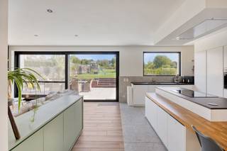 Deze mooie, ruime en lichtrijke woning (2023) bevindt zich op een grond van ruim 18 are. <br /><br />Dit pand omvat een woongedeelte: gelijkvloers: inkomhal, woonkamer met leefkeuken (65 m²), slaapkamer met bijhorende dressing, badkamer (wastafel, inloopdouche, ligbad), toilet en technische ruimte; verdieping: nachthal, vide (speelhoek), 2 zeer ruime slaapkamers en toilet; werkgedeelte (eveneens in te richten als extra woon- en/of slaapruimte): polyvalente ruimte (45 m²) met open keuken, badkamer, berging, archief en toilet.<br /><br />Buiten bevinden zich een ruime oprit voor meerdere wagens, 2 grote terrassen, een omheinde en volledig aangelegde tuin met zeer grote tuinberging. Achterliggend: agrarisch gebied.<br /><br />Deze energiezuinige woning met EPC-label A is volledig geïsoleerd, uitgerust met zonnepanelen, warmtepomp en airconditioning. De elektrische installatie is volledig conform. Er zijn geen asbestmaterialen aanwezig. Niet gelegen in overstromingsgevoelig gebied.<br /><br />Ideaal voor wie graag ruim en modern woont en van thuis uit wil werken, in alle rust met zicht op een groene omgeving en voor wie houdt van een kwalitatieve afwerking.