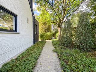 Deze bijzonder verzorgde woning combineert een aangename woonbeleving met een hoogwaardige afwerking, tal van hedendaagse comfortvoorzieningen en een uitzonderlijk aangelegde tuin. Met een bewoonbare oppervlakte van 256 m² beschikt deze perfect instapklare villa over luchtige leefruimtes, een volledig uitgeruste keuken met bijkeuken, drie slaapkamers, een dressing, twee sanitaire ruimtes, een dubbele garage en een fraai aangelegde tuin.<br />De woning is rustig gelegen in een verkeersluwe straat, met terzelfdertijd zeer vlotte verbinding naar uitvalswegen. <br /><br />Gelijkvloers<br />Via de inkomhal (met gastentoilet) bereikt u de verschillende leefruimtes. De trap naar de verdieping is uitgevoerd in eik en wordt gecombineerd met een groot raam waardoor ook de inkomhal aangenaam natuurlijk licht krijgt. De vloer is afgewerkt in natuursteen. De lichtrijke leefruimte met parketvloer, gezellige houtkachel en grote raampartijen biedt een prachtig zicht op de tuin en de vijver, een bijzonder aangename plaats om te vertoeven. <br />De keuken is ruim, voorzien van veel kastruimte en met centraal een mooi keukeneiland, de keuken sluit mooi aan bij de leefruimte en is volledig uitgerust (met een Amerikaanse koelkast en kwalitatieve toestellen waaronder oven, stoomoven, ingebouwde koffiemachine,...). <br />Aansluitend bevindt zich een praktische bijkeuken (met tweede koelkast en oven) en de doorgang naar de droge kelder. Tenslotte is er op het gelijkvloers nog een ruime dubbele garage (met twee poorten, één met elektrische bediening), deze biedt ook plaats aan een wasplaats, stooklokaal en een sanitaire ruimte met douche en lavabo.<br /><br />Verdieping<br />Op de bovenverdieping vinden we drie ruime slaapkamers, een tweede apart toilet, een volledig ingerichte dressing en de badkamer. De eerste slaapkamer is momenteel ingericht als logeerkamer/bureel en is uitgerust met vaste kasten. De master slaapkamer is royaal, met mooi zicht over de tuin en mogelijkheid tot terras. Deze slaapkamer heeft ensuite een lichtrijke badkamer, prachtig uitgerust met inloopdouche, vrijstaand bad en een dubbel lavabomeubel, een zalige plaats om te ontspannen.<br /><br />Buitenomgeving<br />Hier waant u zich in een paradijs, een mooie volgroeide tuin, 100 % privacy en 2 rustgevende waterpartijen met koi-vissen. Het mooie zonneterras is voorzien van zonnewering en verwarming. Als kers op de taart is er een gezellig bijhuis, de Jotul houtkachel en overkapping met buiten-barbecue laten u hier genieten van zalige winter- én zomeravonden! De mooi aangelegde tuin vormt een verlengstuk op de leefruimte met volop mogelijkheden om in alle rust en privacy van uw buitenomgeving te genieten. <br />Praktisch zijn de 2 private staanplaatsen. <br /><br />Afwerking: alle materialen zijn hoogwaardig, kwalitatief en in perfect onderhouden staat waaronder: natuursteen vloeren, parketvloeren, korian werkbladen, prachtige raambekleding met elektrische bediening, verlichting die behouden blijft, stijlvolle eiken deuren in lichte afwerking,...<br />Technische uitrusting: airco in de leefruimtes en master-slaapkamer, alarmsysteem, elektrische rolluiken (muv bovenverdieping), zonnewering elektrisch bediend, terras voorzien van zonneluifel en warmte-elementen, geluidsinstallatie, tuin uitgerust met beregening en sprinklers, vijvers met een zuiveringssysteem en recyclage van water, de woning heeft zonnepanelen (24 m², 3675 Wp), 3 regenwaterputten perfect voor beregening van de tuin.<br /><br />EEN WONING MET BIJZONDER EN COMPLEET WOONCOMFORT OP EEN PRACHTIG PERCEEL! Een oase van rust, waar genieten en comfortabel leven voorop staan!<br />Meer weten? Bel ons vandaag nog voor een bezoek en wij leiden u graag rond in deze mooie eigendom.