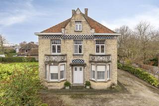 Dit charmante huis uit 1914 is een ware parel die zijn authentieke karakter tot op vandaag heeft behouden. Gelegen op een uitzonderlijk perceel van 1.500 m² biedt deze woning niet alleen een sfeervolle thuis, maar ook extra potentieel dankzij de twee loten bouwgrond die zich in de tuin bevinden.Bij het betreden van de woning kom je in een ruime marmeren inkomhal die meteen de tijdloze elegantie van het huis benadrukt. De authentieke vloeren in de woning zorgen voor een warme, historische sfeer. De zeer ruime woonkamer bestaat uit een zit- en eetgedeelte en sluit aan op een karaktervolle rotonde met prachtig zicht op de groene tuin.Op het gelijkvloers is er aan de voorzijde nog een ruime voorplaats, ideaal als bureau of praktijkruimte. Aan de achterzijde bevindt zich de keuken met directe toegang tot de tuin.De eerste verdieping telt vier grote, volwaardige slaapkamers en een badkamer met ligbad en lavabo. Via een vaste trap bereik je de zolderverdieping, waar het mogelijk is om een volwaardige extra verdieping te creëren, wat tal van bijkomende mogelijkheden biedt.Deze woning is niet enkel een plek om te wonen, maar een unieke kans om een stukje architecturale geschiedenis uit het begin van de 20e eeuw te bezitten en te vernieuwen naar eigen smaak. Bovendien ligt het huis op slechts 10 minuten wandelafstand van het stadscentrum, een zeldzame combinatie van ruimte, karakter en ligging.De algemene voorwaarden van Dewaele DIY kunt u steeds raadplegen via dewaele.com.