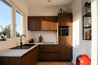 <p>Op een gunstige locatie in Wilrijk, op de grens met Edegem en op wandelafstand van Fort V, bevindt zich dit stijlvol en volledig gerenoveerd appartement. De combinatie van een hedendaagse afwerking, bijzonder veel natuurlijke lichtinval en energiezuinige technieken zorgt voor een comfortabel en aangenaam woongevoel.<br />Het appartement wordt gekenmerkt door hoge plafonds, grote raampartijen met driedubbele beglazing en een mooie visgraatvloer die als rode draad doorheen het interieur loopt. De warme notelaartinten in de keuken sluiten perfect aan bij de eigentijdse afwerking van het geheel.<br />Met EPC-label A, zonnepanelen, verwarming via warmtepomp, airco’s voor warmen en koelen, een privatieve berging én een afzonderlijke garagebox is dit appartement bovendien helemaal klaar voor comfortabel en energiezuinig wonen.</p>
<p><strong>2<sup>DE</sup> VERDIEPING</strong><br />Via de <strong>inkomhal</strong> betreedt u het appartement. De hal is afgewerkt met een stijlvolle visgraat vinylparket en geeft toegang tot het afzonderlijke gastentoilet, voorzien van een handenwasser.<br />De lichtrijke <strong>woonkamer</strong> vormt samen met de <strong>open keuken</strong> een aangename en open leefruimte. Dankzij de grote raampartijen en hoge plafonds geniet deze ruimte van bijzonder veel natuurlijke lichtinval.<br />De open keuken werd afgewerkt in een warme notelaarkleur en werd uitgerust met een inductiekookplaat, ingebouwde koelkast met diepvriesvak, vaatwasser, combi-oven en spoelbak.<br />Ook hier werd gekozen voor visgraat vinylparket, waardoor de leefruimte één mooi en samenhangend geheel vormt.<br />Vanuit de woonkamer is er toegang tot een praktische <strong>berging/wasplaats</strong>, met plaats voor een wasmachine en droogkast en extra opbergruimte dankzij de aanwezige wandrekken.<br />De <strong>badkamer</strong> is volledig betegeld en modern afgewerkt. Ze beschikt over een ruime inloopdouche, een handdoekradiator en een stijlvol badkamermeubel in Mortex. De verlichte spiegel zorgt voor een extra verfijnde uitstraling.<br />De ruime <strong>slaapkamer</strong><strong> </strong>eveneens op visgraat vinylparket biedt verrassend veel plaats. Ook hier zorgen de grote ramen, hoge plafonds en aanwezige gordijnen voor een aangename en sfeervolle ruimte.</p>
<p><strong>Inclusief privatieve kelderberging & garagebox.</strong></p>
<p><strong>BESCHIKBAARHEID<br /></strong>15 mei 2027</p>
<p><strong>BIJZONDERHEDEN<br /></strong>Lift, zonnepanelen, verwarming via warmtepomp, airco’s warmen & koelen, driedubbele beglazing, schrijnwerk in pvc, videofoon.</p>