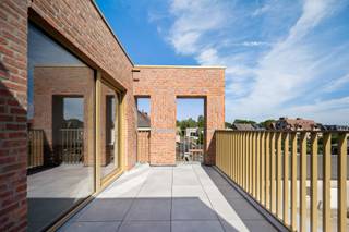 Deze triplexwoning heeft een aparte inkom aan de Stationsstraat en verrast met een moderne en innovatieve indeling. <br /><br />De leefruimte in loftstijl bevindt zich op de tweede verdieping en biedt een open en lichtrijke beleving, met een aansluitende leefkeuken en een extra grote berging. Hier bevindt zich ook een derde toilet, wat het comfort compleet maakt. Het zuidgerichte terras is zijdelings afgeschermd voor optimale privacy.<br /><br />De woning beschikt over twee volwaardige slaapkamers: één op het gelijkvloers en één op de eerste verdieping. Beide slaapkamers zijn ruim genoeg voor een dubbel bed en een dressingkast en hebben elk een badkamer met dubbele wastafel, douche en toilet.<br /><br />Dankzij de flexibele indeling is deze woning geschikt voor een gezin, koppel, maar ook ideaal voor co-housing of eventueel iemand met een zelfstandige activiteit.<br /><br />Extra troef: een zeer ruime garage (aan te kopen voor €40.000,-), gelegen in de Ambachtsstraat. Deze biedt plaats aan een wagen, fietsen, afvalcontainers én heeft de mogelijkheid tot aansluiting van een laadpaal, rechtstreeks verbonden met de meterkast van de woning.<br /><br />*Vloerverwarming mét vloerkoeling, warmtepomp en zonnepanelen inbegrepen<br />*E-peil 10 (ver onder de norm), wat betekent: 5 jaar vrijstelling van onroerende voorheffing<br />*Mogelijkheid aankoop aan 6% BTW.
