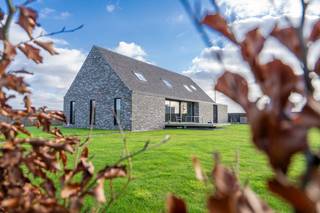De woning, gebouwd in 2019, is ontworpen met oog voor flexibiliteit en duurzaamheid. Het modulaire ontwerp maakt het mogelijk om eenvoudig extra ruimtes toe te voegen of bestaande ruimtes aan te passen of te verwijderen. Perfect voor een groeiend gezin of wie zijn woonruimtes wil personaliseren.3 ruime slaapkamers2 moderne badkamersVoorzien van geothermie en driedubbelglas, een energiezuinige en duurzame oplossing voor verwarming en koeling.Grote raampartijen zorgen voor een overvloed aan natuurlijk licht en een aangename woonbeleving.Indrukwekkend magazijn en kantoorruimte:Naast de woning bevindt zich een zeer groot magazijn van maar liefst 200 m², ideaal voor ondernemers, hobbyisten of als opslagruimte. De 50 m² kantoorruimte biedt een professionele omgeving om te werken, vergaderen of klanten te ontvangen. Deze combinatie van wonen en werken op één locatie maakt dit pand uniek.Tuin en perceelHet perceel van 4640 m² biedt volop ruimte en privacy. Of u nu houdt van tuinieren, buitenactiviteiten of gewoon geniet van rust en ruimte, deze eigendom heeft het allemaal.Waarom kiezen voor deze woning?Moderne, duurzame woning met uitbreidingsmogelijkhedenGrote opslag- en werkruimtes, perfect voor zelfstandigenRustige ligging in Deinze met een royaal perceelGeothermische verwarming voor een energiezuinige toekomstBent u op zoek naar een eigendom die wonen en werken combineert op een ruim perceel? Aarzel niet en plan vandaag nog een bezoek aan Kouter 253 in Deinze!