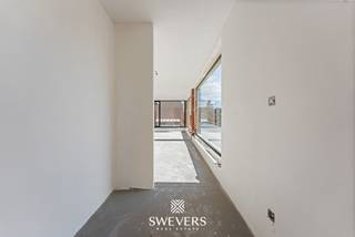 Aan de Koolmijnlaan 69 bus 1.2 in Houthalen bevindt zich dit 3-slaapkamer appartement met een bewoonbare oppervlakte van 107,65 m². Het appartement maakt deel uit van een nieuwbouwproject dat in 2026/2027 wordt opgeleverd en combineert, energiezuinigheid met een hedendaagse afwerking en een uiterst praktische indeling. Dankzij de aanwezigheid van een lift is dit een interessante keuze voor wie zorgeloos wil wonen en bovendien heb je hier alle nodige voorzieningen binnen handbereik. <br /><br />De leefruimte en keuken vormen samen één ruim en open geheel van maar liefst 44 m² en vormen het centrale hart van de woning. De open indeling creëert een aangename, lichte leefomgeving waarin koken, tafelen en ontspannen moeiteloos in elkaar overvloeien. De zithoek biedt met 20 m² alle ruimte voor een royale en gezellige inrichting, terwijl de keuken met 24 m² bijzonder ruim is opgevat. Hier is volop plaats voor een functionele én stijlvolle keukeninrichting met kookeiland en gezellige eethoek. Het resultaat is een open en uitnodigende leefruimte die perfect aansluit bij het dagelijkse gezinsleven, maar evengoed alle ruimte biedt om familie en vrienden te ontvangen.<br /><br />Een belangrijk pluspunt zijn de twee terrassen. Het eerste terras van 22m² sluit naadloos aan op de leefruimte. Het tweede terras van 15m² bevindt zich aan de achterzijde en sluit aan op de slaapkamers. Hierdoor beschikt u over veel buitenruimte, wat zeldzaam is bij appartementen van dit type. Met andere woorden, u kan hier naar eigen wens genieten van de buitenruimte op maar liefst elk moment van de dag.<br /><br />Het appartement beschikt over drie slaapkamers. De grootste slaapkamer heeft een oppervlakte van 15,75 m² en biedt voldoende ruimte voor een tweepersoonsbed en kasten. De twee andere slaapkamers meten 10,20 m² en 10 m². Deze kunnen perfect worden ingericht als kinderkamer, logeerkamer, bureau of dressing. Die flexibiliteit maakt het appartement geschikt voor verschillende levensfases.<br /><br />De badkamer is praktisch ingedeeld en sluit aan bij het hedendaagse comfort dat men van een nieuwbouwappartement verwacht. Daarnaast is er een aparte berging aanwezig. Deze ruimte is ideaal voor voorraad, poetsmateriaal, wasvoorzieningen of extra opbergmogelijkheden.<br /><br />Het gebouw is voorzien van een lift, wat het comfort verhoogt voor bewoners en bezoekers. Ook de aanwezigheid van zonnepanelen en warmtepomp is een sterk pluspunt. Ze dragen bij aan een energiezuiniger geheel en passen binnen de verwachtingen van wie vandaag bewust kiest voor een recent en toekomstgericht appartement. De kelder biedt parkeerplaatsen en bergingen aan die naar eigen wens optioneel bij aan te kopen zijn. <br /><br />De ligging aan de Koolmijnlaan in Houthalen is bijzonder functioneel. Winkels bevinden zich op ongeveer 500 meter, waardoor dagelijkse boodschappen snel geregeld zijn. Openbaar vervoer ligt op circa 180 meter en is dus vlot bereikbaar te voet. Scholen bevinden zich op ongeveer 2 kilometer, net als ontspanningsmogelijkheden en restaurants. Alles wat u vaak nodig heeft, ligt op korte afstand.<br /><br />Ook de verbinding met de ruimere omgeving is een voordeel. De snelwegen liggen op ongeveer 1,5km, waardoor verplaatsingen richting omliggende gemeenten en steden vlot verlopen. U geniet hier van de ideale centrale ligging.<br /><br />Belangrijk om te weten is bovendien dat de grondwaarde hier vastgelegd werd op €51 000. Op deze som betaal je dus slechts 12% registratierechten. Op de overige constructiewaarde van €244 000 is er 21% btw verschuldigd.<br /><br />Dit instapklare appartement aan de Koolmijnlaan 69 bus 1.2 in Houthalen biedt 107,65 m² wooncomfort, drie slaapkamers, een ruime leefruimte, een keuken met kookeiland en 2 terrassen. De nieuwbouwkwaliteit, lift, zonnepanelen, warmtepomp en gunstige ligging maken dit appartement tot een sterke keuze voor kopers die zoeken naar comfort en zorgeloos wonen. Plan een persoonlijke rondleiding en ontdek ter plaatse hoe dit appartement aansluit bij uw plannen. Voor meer informatie, bel 011 255 155. <br /><br />Prijs exclusief 21% BTW en exclusief andere belastingen en toeslagen: 295.000 euro<br />Prijs inclusief 21% BTW, exclusief andere belastingen en toeslagen: 346.240 euro