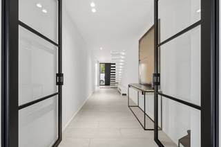 <p><span>Aan het einde van de rustige, doodlopende Pruimelaarstraat, ligt deze luxueus afgewerkte woning (2019) met een verzorgd aangelegde tuin, camera’s, alu antraciet buitenschrijnwerk (Reynaers), wachtleiding voor oplaadpunt, alu poort, geïntegreerde pakketbrievenbus, maatkasten, etc. De gelijkvloerse verdieping is voorzien van hoogwaardige designbinnendeuren van Anyway Doors. De EPC-score van 89 (Label A) werd bereikt door integratie van: algemene vloerverwarming, condensatieketel, 18 zonnepanelen en dikke isolatielagen. De ruime leefruimte beschikt over een tv-meubel (maatwerk), geïntegreerde gashaard (M-Design), afstandsbediende elektrische binnenlamellen (Somfy), ingebouwde speakers, grote alu schuiframen (Reynaers), gepolierde betonvloer en plafondhoge deuren (Nordex). Let in de aangelegde tuin met veel privacy op de prijzige overdekte terrasconstructie (Brustor), de robotmaaier, het bijgebouw en de tuinverlichting (app). In de luxueuze keuken (Grando), spotten we veel (verborgen) bergruimte, Dekton werkbladen, een groot kookeiland (6 zitplaatsen), Miele toestellen (oven, microgolfoven, koffiemachine, koelkast, diepvries), plus een kookplaat met geïntegreerde afzuiging. Opbergruimte is beschikbaar in een wasplaats, een droge kelder en een technische ruimte. In de toiletten is zelfs de rolhouder geïntegreerd in de muur. De luxe-badkamer is groot genoeg voor de inloopdouche (stalen deur) en het dubbele badkamermeubel (maatwerk). Alle kamers bieden plaats voor een dubbel bed. De exclusieve handgemaakte trap van Genico met Corian afwerking en geïntegreerde LED-verlichting, geeft aan van welk hoog niveau de afwerking wel is.</span></p>