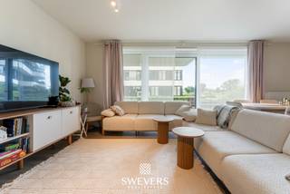 Voor meer info en foto’s, surf naar www.swevers.be – Dit instapklare gelijkvloerse appartement ligt aan de achterzijde van residentie Zuidzicht op Scheepvaartlaan 48/0.05 in Hasselt. Dankzij deze rustige ligging geniet u van zicht op de binnentuin en een glimp van het Albertkanaal. Het appartement werd gebouwd in 2016, is bereikbaar met de lift en biedt een bewoonbare oppervlakte van 74,38 m². De indeling bestaat uit een inkomhal, twee slaapkamers, een badkamer en een ruime leefruimte met open keuken. De woonkamer en keuken vormen samen een aangename leefzone met veel licht en directe toegang tot het overdekte terras van maar liefst 30 m². Dit terras is een grote troef en voelt aan als een verlengstuk van de leefruimte. De hoofdslaapkamer is volwaardig ingericht, terwijl de tweede kamer perfect dienst kan doen als bureau, kinderkamer, logeerkamer of dressing. De badkamer beschikt over een ligbad met douchescherm en een ruime wastafel. Met EPC-score B is het appartement bovendien energiezuinig. Het pand is momenteel verhuurd aan 890 euro per maand, plus 125 euro gemeenschappelijke kosten, wat het ook interessant maakt als investering. Een ondergrondse autostaanplaats kan optioneel aangekocht worden voor 32.500 euro. Dankzij de ligging nabij het centrum van Hasselt bevinden winkels, horeca, ontspanning, scholen, openbaar vervoer en de autosnelweg zich allemaal vlot bereikbaar. Voor meer informatie, bel 011 255 155. Bron bewoonbare oppervlakte: EPC – verslag.