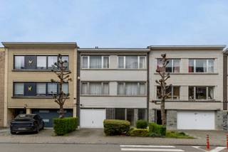 Immo Pické biedt U deze statige en gunstig gelegen eengezinswoning aan gelegen in de nabijheid van winkels, openbaar vervoer, scholen en de belangrijkste verbindingswegen (o.a. R0). Deze woning heeft twee afzonderlijke ingangen en is bijgevolg uitermate geschikt voor het uitoefenen van een vrij beroep of de bewoning als zorgwoning. Via de eerste inkomhal begeven we op het gelijkvloers naar een ruimte die actueel bestaat uit een hal, een ingerichte keuken, een woonkamer met slaaphoek en een ingerichte badkamer met douche en toilet. Via de tweede inkomdeur betreden we de tweede inkomhal die uitgeeft op een garage voor één wagen. Via een statige trap begeven we ons naar de eerste verdieping die bestaat uit een hal, een zeer lichtrijke woonkamer met aangrenzende eetkamer (L-vorm), een ruime gedeeltelijk ingerichte keuken en een sanitaire ruimte. Op deze verdieping vinden we ook een terras. Op de tweede verdieping kunnen we een nachthal, 4 slaapkamers en een badkamer terugvinden. De woning is volledig onderkelderd. Achter de woning vinden we een leuk terras en een volledig ingerichte stadstuin. Open autostaanplaats aanwezig voor de garage.