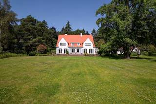 <p><span>Dit bijzondere eigendom is gelegen op een zeer rustige en groene locatie te Kapellen nabij Royal Antwerp Golf Club. Rust, een groene omgeving alsook een goede verbinding met het centrum van Heide-Kalmthout zijn troeven van deze locatie. Het domein van ruim 1 hectare groot omvat een recent gerenoveerde villa, een guesthouse, garage gebouw, zwembad en tennis terrein.</span></p><p><span> </span></p><p><span>Hoofdgebouw</span></p><p><span>U betreedt de villa middels de centrale inkomhal op parketvloer met trap naar de eerste verdieping alsook vestiaire, gastentoilet en toegang tot de kantoorruimte. De leefruimte werd opgedeeld in een zitkamer met open haard, aangename eetruimte en een tv-kamer. Deze drie ruimtes kunnen worden afgesloten middels schuifdeuren. Smaakvol ingerichte keuken met diverse inbouwtoestellen waaronder vaatwasser, koelkast, oven, gasvuur en dubbele spoelbak. Vanuit de keuken toegang tot de bijkeuken met kasten en toegang naar de kelderruimte. </span></p><p><span><br />1e Verdieping</span></p><p><span>Middels de trap bereikt u ruime nachthal met loungeruimte. De masterslaapkamer omvat een ruime dressing met ingemaakte kasten alsook een badkamer met bidet, toilet, douche, ligbad en dubbele lavabo. Tweede ruime slaapkamer met dressing en privatieve badkamer met ligbad, toilet en lavabo. Derde slaapkamer met lavabo, separate badkamer en een vierde slaapkamer met ingemaakte kasten. </span></p><p><span> </span></p><p><span>2e Verdieping / zolder</span></p><p><span>Toegang naar de zolderruimte middels vlieringtrap. De zolderruimte is opgedeeld in drie compartimenten. </span></p><p><span> </span></p><p><span>Kelder</span></p><p><span>De kelderruimte werd ingedeeld in verschillende ruimtes waaronder een wijnkelder, berging en een wasplaats met strijkgedeelte met aansluitingen voor wasmachine en droogkast. Tevens is er een speelkamer of polyvalente ruimte en een relaxgedeelte of wellness met tevens toegang naar buiten toe (nota; deze ruimtes zijn nog niet gerenoveerd). Apart technisch lokaal met CV installaties (condenserende gasketels Buderus) alsook waterontharder. </span></p><p><span> </span></p><p><span>Guesthouse en polyvalent gebouw</span></p><p><span>Op het domein is een apart guesthouse in dezelfde stijl als het hoofdgebouw met 2 slaapkamers, 2 badkamers, een keuken en 2 garages. Een derde gebouw is polyvalent te gebruiken en bestaat uit een grote kantoorruimte en 2 extra garages.</span></p><p><span> </span></p><p><span>Bijzonderheden</span></p><p><span>Dit domein op ruim 1 hectare grond werd gerealiseerd in de jaren '50 en in 2022 werd de villa volledig gerenoveerd naar hedendaagse normen van luxe, comfort en afwerking. De villa heeft hiermee ook een EPC label B (172 KWH). </span></p><p><span>De tuin werd ook deels opnieuw aangelegd en hier treft u behalve een zwembad ook een tennis terrein. </span></p><p><span> </span></p><p><span>Meer inlichtingen via ons kantoor</span></p>