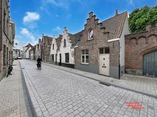 Deze charmante TRAPGEVEL WONING bevindt zich in de Sint-Jorisstraat, op een steenworp afstand van het bruisende centrum van Brugge. Na 2000 werd de woning grondig VERNIEUWD , waarbij onder andere een nieuwe betonvloerplaat, geïsoleerde ondervloer en chape werd geplaatst. De elektriciteit en sanitair werden eveneens aangepast. Ook het metselwerk en de dakconstructie zijn stevig aangepakt, waardoor het pand in UITSTEKENDE STAAT verkeert.<br /><br />Binnen geniet u van een lichtrijke en gezellige living van 26,5 m² die uitgeeft op een RUIM BUITEN TERRAS ideaal voor ontspanning en gezellig samenzijn. De aangrenzende keuken is voorzien van moderne toestellen en profiteert van veel natuurlijke lichtinval. Verder telt de woning een praktische badkamer met douchecabine, lavabo en toilet. Op de eerste verdieping bevinden zich TWEE RUIME SLAAPKAMERS van respectievelijk 13 en 14,75 m², beiden afgewerkt met een warm, rustiek laminaat, perfect voor een comfortabele nachtrust.<br /><br />De woning is ASBEST VEILIG en beschikt over een GOEDGEKEURDE ELEKTRISCHE INSTALLATIE. Met een GUNSTIGE EPC-waarde van 226 kWh/m² per jaar (label C) bent u verzekerd van een ENERGIEZUINIG en comfortabel thuis. <br /><br />Troeven :<br />* authentieke trapgevel<br />* mooi buitenterras<br />* asbestveilig<br />* Label C : geen renovatieplicht<br />* geïsoleerde ondervloer + nieuwe leidingen <br />* nieuw dak <br />* goedgekeurde elektriciteit <br /><br />Voor meer informatie of een bezoek kunt u contact opnemen via 050/333976 of 0476/270379 (buiten kantooruren).
