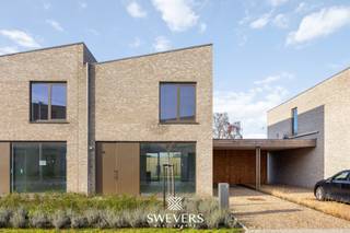Voor meer info en foto’s, surf naar www.swevers.be – In een rustige, maar centraal gelegen buurt in Leopoldsburg staat deze instapklare nieuwbouwwoning uit 2025 te koop. De halfopen bebouwing is volledig nieuw en combineert hedendaags wooncomfort met een doordachte indeling. Met een bewoonbare oppervlakte van 144,44 m² op een perceel van 291 m² biedt deze woning drie slaapkamers, een moderne leefruimte, open keuken, twee bergingen en twee toiletten. De lichtrijke leefruimte sluit via een schuifraam aan op het zuidoostelijk georiënteerde terras en de tuin – ideaal voor ochtend- en middagzon. De woning beschikt bovendien over een carport. Alle voorzieningen bevinden zich op wandelafstand: scholen op 200 meter, station op 650 meter en het centrum op slechts 1 km. Ook de snelwegen zijn vlot bereikbaar. Kortom, een comfortabele gezinswoning op een gunstige locatie. Bovendien biedt deze woning een voordelig fiscaal voordeel: de grondwaarde bedraagt € 80 000 (12% registratierechten), terwijl de constructiewaarde van € 269 500 onder het 6 % btw-tarief valt. Voor meer informatie, bel 011 255 155. Bron bewoonbare oppervlakte: EPC – verslag.