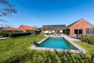 <strong>Riante, gerenoveerde hoeve (1932) nabij Provinciaal Groendomein Prinsenpark op privé-domein van ca. 2 hectare. De hoeve met paardenstallen werd in 2001 en verder in 2020 (dak, zonnepanelen) en 2025 (verwarming) doorgedreven gerenoveerd en omvat 4 à 6 slaapkamers, 2 badkamers,1 douchekamer, een thuiskantoor, een poolhouse en een afzonderlijke paardenstal (9 boxen) met directe toegang tot de aangrenzende weides en zandpaddock. De weides zijn volledig omheind en voorzien van automatische drinkbakken voor weidedieren. De hoevevilla zelf ademt authenticiteit en warmte en is kwalitatief afgewerkt en zeer ruim. Zij biedt een combinatie van wooncomfort, praktische voorzieningen (o.a. douchekamer in het poolhouse, riante benendenbadkamer, etc.) en beschikt over een grote inpandige garage die bijkomend gebruikt kan worden voor opslag of betrokken binnen het woongeheel. De woning beschikt over een uiterst gunstige EPC-score van 113kWh/m²/jaar (label B) en is asbestveilig. </strong><br /><br /><strong>De ligging van het domein is uniek en de troef bij uitstek. De woning is zuid(west)georiënteerd en gelegen in agrarisch gebied. Er is voldaan aan voorwaarden 'zonevreemde woning', wat maakt dat het domein ook bewoond kan worden en niet louter moet dienen in het kader van (para-)agrarische activiteiten. Het uitgestrekt gebied Wenen-Geenend-Prinsenpark is één van de mooiste en meest natuurlijke buurten te Retie. De residentiële aard van de wijk (ondanks agrarisch gebied) maakt dat deze wijk uiterst rustig is. Bovendien is de woning gelegen op wandelafstand van natuurgebieden (o.a. Prinsenpark), wandel- en fietsroutes, sportvoorzieningen ('t Vossekot), Meulenzicht en De Watermolen Retie, etc. </strong><br /><br /><em>Gelijkvloers niveau:<br /></em><strong><br /></strong><span>Via de inkomhal met ruimte voor garderobe en gastentoilet heeft u toegang tot de thuiskantoorruimte en de woonkamer. De leefruimte met fraai zicht op de tuin en achterliggende paardenweiden is opgedeeld in een eetgedeelte en een gezellige zithoek op tussenniveau. Onder deze zithoek is een authentieke bergkelderruimte aanwezig. Vanuit de lichte leefruimte heeft u verder toegang tot de keuken met op zijn beurt toegang naar de buitenhal. De keuken is open (verbonden met de woonkamer), enorm lichtrijk en volledig uitgerust. Aan deze keuken bevindt zich de hal die toegang geeft tot de tuin, een riante benedenbadkamer (met douche, twee lavabo's en inbouwkasten), de wasplaats en grote garage met sectionaalpoort.</span><br /><br /><em>Bovenverdieping:<br /></em><strong><br /></strong><span>Op het eerste verdiep bevindt zich o.a. een ruime hoofdslaapkamer met 2 inloopdressings. De bovenbadkamer is uitgerust met ligbad, inloopdouche en toilet. Verder zijn er op deze verdieping bijkomend 3 volwaardige slaapkamers, ideaal voor kinderen, logés of extra opslag, werk-/hobbyruimtes. </span><br /><br /><em>Stalgebouw en buitenruimte:<br /></em><strong><br /></strong><span>Het eigendom is verder bijzonder geschikt voor dierenliefhebbers. De stalaccommodatie is voorzien van 9 ruime paardenboxen, elk uitgerust met automatische drinkbakken. Verder is er ruimte voor opslag of inrichting van fokfaciliteiten, zadelkamer, etc. De paarden (of andere weidedieren) kunnen via de binnenkoer rechtstreeks naar de aanpalende, ruime en opgedeelde weides en zandpaddock, wat zorgt voor een uiterst optimale leef- en trainingsomgeving. De achterliggend gelegen weides zijn allen stijlvol afgemaakt in hout en voorzien van drinkwater.</span><br /><br /><span>Bijzonderheden</span>:<br />- Uitzonderlijke ligging: uitgestrekt domein nabij Prinsenpark<br />- Nabij Nederland en verbindingsweg E34 (Antwerpen - Eindhoven)<br />- Regio met sterke affiniteit voor paarden: diverse stoeterijen, maneges en hippische faciliteiten<br />- Centrale ligging: het Azelfhof, Sentower Park en De Peelbergen zijn goed bereikbaar<br />- Uiterst zorgeloze woning: o.a. B-label en asbestveilig