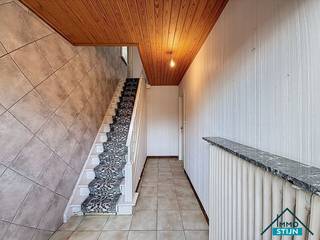 Deze woning geniet van een vlotte verbinding naar diverse winkels, het openbaar vervoer en de E403, en vormt zo een ideale uitvalsbasis voor wie comfort en bereikbaarheid wil combineren.<br />Bij het betreden van de woning kom je terecht in de inkomhal, die in verbinding staat met de woonkamer en de eerste verdieping. De lichtrijke woonkamer biedt voldoende plaats voor een gezellig zit- en eetgedeelte en sluit naadloos aan op de keuken. De ruime keuken is voorzien van een geïnstalleerde keuken, biedt plaats voor een ontbijttafel en staat in verbinding met de kelder en de wasplaats. Vooraleer je de trap naar de kelder neemt, is er nog een handige bergruimte. De droge kelder zorgt voor extra stockage. De wasplaats is uitgerust met de nodige aansluitingen voor wasmachine en droogkast en beschikt over een ingebouwde kast voor extra voorraad. Van hieruit heb je toegang tot het gastentoilet, de badkamer en de buitenruimte. In de badkamer zijn een ligbad en lavabo aanwezig. Op de eerste verdieping bevindt zich de nachthal met toegang tot drie slaapkamers, een dressing en een berging. Via het trapluik in de dressing bereik je de zolder, die extra opbergruimte biedt. De volledige woning is voorzien van rolluiken, wat zorgt voor extra comfort en privacy. Buiten geniet je van een aangelegde tuin met tuinhuis, een tuinberging, een garage met aanpalende berging en een carport. Naast de woning is er een oprit die toegang geeft tot de garage en carport, wat ruime parkeermogelijkheden biedt. (sted.inl.: Vg,WgLk,Gmo,Gvkr,Vv)