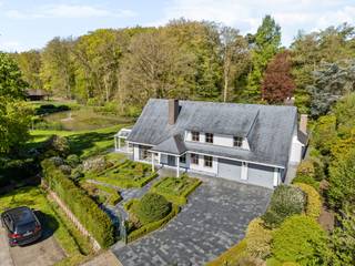 Charmante villa met ruime uitbreidingsmogelijkheden op een uniek privé-domein grenzend aan natuurgebied te Schilde<br /><br />In één van de meest gegeerde en residentiële buurten van Schilde, discreet gelegen aan het einde van een doodlopende straat, bevindt zich deze karaktervolle villa op een perceel van 4968m². Een locatie waar rust, privacy, natuurbeleving en comfort naadloos samenkomen.<br /><br />Indeling gelijkvloers:<br />De villa verwelkomt u via een ruime en lichtrijke inkomhal met vestiaire en gastentoilet. Vanuit hier bereikt u de aangename leefruimte met open haard en grote raampartijen, die zorgen voor een prachtig uitzicht op de fraai aangelegde tuin. Aansluitend bevindt zich een sfeervolle leefveranda, volledig omringd door schuiframen en voorzien van automatische zonnescreens, zodat u het hele jaar door geniet van een maximale lichtinval en een harmonieus zicht op het groen.<br /><br />De volledig uitgeruste keuken biedt eveneens zicht op en directe toegang tot het terras en wordt vergezeld door een praktische berging. Aansluitend bevindt zich een tweede gezellige leef- en eetruimte, voorzien van een houtkachel, wat deze ruimte bijzonder warm en uitnodigend maakt. Tevens is er een aparte bureauruimte, ideaal voor wie praktijk- of kantooractiviteiten aan huis wenst. De inpandige garage met automatische poort biedt plaats aan twee voertuigen.<br /><br />Eerste verdieping:<br />De nachthal leidt naar de master bedroom met ensuite badkamer, aangevuld met drie comfortabele, volwaardige slaapkamers. Daarnaast is er een tweede badkamer met douche en een bijzonder ruime, functionele wasplaats.<br /><br />Tuin en buitenbeleving:<br />De zuidwest-georiënteerde tuin vormt een ware oase van rust, met weidse vergezichten en een bijzonder harmonieuze groenbeleving. De tuin werd smaakvol aangelegd.<br /><br />Bijzonderheden:<br />- Maximale privacy, prestigieuze ligging & ideale zonoriëntatie<br />- Renovaties: 1997 (aanbouw leefruimte) – 1999 (gedeeltelijk buitenschrijnwerk)<br />- Verwarming op aardgas (Viessmann) via radiatoren en convectoren<br />- Dubbele beglazing (hout & aluminium)<br />- Rolluiken aanwezig<br />- Videofonie & automatische toegangspoort<br />- Oprit met plaats voor ca. 6 wagens<br />- Bergzolder toegankelijk via vlizotrap