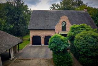Op een bijzonder mooie en rustige locatie in het residentiële Schotenhof bevindt zich deze karaktervolle familievilla, omgeven door een volwassen tuin en genietend van een uitzonderlijke privacy.<br /><br />De eigendom combineert een royaal woonvolume met een warme, tijdloze uitstraling en een sterke verbondenheid met de tuin. Dankzij de uitstekende zuidoriëntatie, de verschillende leefruimtes en het charmante eiken bijgebouw is dit bovenal een huis waar binnen- en buitenleven op een vanzelfsprekende manier in elkaar overvloeien.<br /><br />Ook de ligging is bijzonder aangenaam: discreet en groen, maar tegelijk op korte afstand van zowel Schoten als ’s-Gravenwezel, met scholen, winkels en gerenommeerde sportclubs in de onmiddellijke omgeving.<br /><br />Een huis met ruimte en karakter<br /><br />De woning wordt benaderd via een royale voortuin met sfeervolle waterpartij. Enkele treden leiden naar de brede inkomdeur en de ruime ontvangsthal, van waaruit dubbele glazen deuren meteen een mooie doorkijk bieden naar de leefvertrekken en het groen rondom.<br /><br />De natuurstenen vloer loopt harmonieus door naar de verschillende leefruimtes. Het iets hoger gelegen salon met open haard vormt een intieme en sfeervolle plek, terwijl het aansluitende eetgedeelte zich naar de tuin richt. Grote raampartijen aan zowel voor- als achterzijde zorgen doorheen de woning voor veel natuurlijk licht en een voortdurend contact met de omgeving.<br /><br />Centraal in het dagelijkse leven staat de ruime leefkeuken. De karaktervolle AGA vormt er het hart van de ruimte, aangevuld met Miele-inbouwapparatuur en een royaal eiland waaraan ook informeel kan worden gegeten. Een glazen deur opent rechtstreeks naar het terras en de zuidgerichte tuin.<br /><br />Aansluitend bevindt zich een afzonderlijke kamer die zich uitstekend leent als bureau, bibliotheek of polyvalente ruimte en eveneens toegang biedt tot het terras. Een ruime bijkeuken zorgt voor het nodige praktische comfort.<br /><br />De dubbele inpandige garage biedt plaats aan twee wagens en beschikt over bijkomende bergruimte.<br /><br />Privévertrekken<br /><br />Op de eerste verdieping bevinden zich de hoofdslaapkamer en drie bijkomende slaapkamers, samen met twee badkamers. Talrijke ingemaakte kasten zorgen voor een bijzonder praktische indeling.<br /><br />Een afzonderlijke trap leidt verder naar een verrassend royale bovenverdieping met mezzanine. Een ruimte die zich naar eigen behoefte laat invullen als bijkomende slaapkamer, gastenverblijf, hobbyruimte of thuisbureau. Ook de zolder is vanaf hier bereikbaar.<br /><br />De woning beschikt bovendien over een zeer ruime kelderverdieping, waardoor ook aan berging en technische ruimte geen gebrek is.<br /><br />Een tuin in alle privacy<br /><br />De volwassen tuin vormt een essentieel onderdeel van de beleving van deze eigendom. De zuidelijke oriëntatie, het vele groen en de afwezigheid van inkijk creëren een bijzonder aangename en besloten sfeer.<br /><br />Een mooi uitgevoerd eiken bijgebouw, voorzien van verwarming en bergruimte, geeft de tuin nog een extra dimensie en biedt mogelijkheden voor wie op zoek is naar een afzonderlijke werk-, hobby- of ontspanningsruimte.<br /><br />Een eigendom die niet zozeer overtuigt door één afzonderlijk element, maar door het geheel: ruimte, privacy, groen en een bijzonder aangename woonkwaliteit op één van de meest gegeerde residentiële locaties van Schoten.<br /><br />Bijzonderheden<br /><br />• Residentieel en discreet gelegen in Schotenhof<br />• Op korte afstand van Schoten en ’s-Gravenwezel<br />• Royale familievilla met vijf mogelijke slaapkamers<br />• Twee badkamers<br />• Ruime leefkeuken met AGA<br />• Zuidgerichte tuin met uitzonderlijke privacy<br />• Verwarmd eiken bijgebouw<br />• Dubbele inpandige garage en bijkomende garage<br />• Royale kelder- en bergruimtes<br />• Nabij scholen, winkels en gerenommeerde sportfaciliteiten