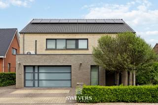 Voor meer info en foto’s, surf naar www.swevers.be – Deze instapklare open bebouwing aan de Schutenseweg 95 in Zonhoven biedt maar liefst 267 m² woonoppervlakte op een perceel van 10a54. De woning uit 2005 combineert ruimte, comfort en veelzijdigheid, ideaal voor grote gezinnen, zorgwoning of wie wonen en werken wil combineren.<br />Via de imposante inkomhal bereikt u de lichtrijke leefruimte van 41 m² met grote raampartijen en directe toegang tot de tuin. Aansluitend bevindt zich een afzonderlijk bureau dat eenvoudig opnieuw bij de woonkamer kan worden betrokken. De ruime leefkeuken van 22 m² beschikt over alle nodige inbouwtoestellen, veel bergruimte en plaats voor een grote eettafel. Verder zijn er op het gelijkvloers een wasplaats met maatkasten, een extra douche en een praktische vestiaire. Een grote troef is de voormalige inpandige garage die werd ingericht als praktijk- of hobbyruimte van circa 34 m² met eigen ingang. Deze ruimte biedt tal van mogelijkheden als kantoor, atelier, zorgunit of logeerverblijf. Op de verdieping bevinden zich vier slaapkamers, waaronder een masterbedroom met his-and-her inloopdressing. De vernieuwde badkamer is uitgerust met een ruime dubbele inloopdouche, dubbele lavabo en maatkasten. Daarnaast is er een afzonderlijk toilet aanwezig. De woning is volledig onderkelderd met ongeveer 60 m² extra bergruimte en beschikt bovendien over een zolder van circa 60 m² met uitbreidingsmogelijkheden. Buiten geniet u van een verzorgde tuin met terras, fruitbomen, bessenstruiken en fietsenstalling. Extra comfort wordt geboden door airco’s, zonnepanelen met thuisbatterij en een laadpaal voor elektrische voertuigen. De rustige ligging combineert een vlotte bereikbaarheid met scholen, openbaar vervoer, winkels, Hasselt en de autosnelweg in de nabije omgeving. Voor meer informatie, bel 011 255 155. Bron bewoonbare oppervlakte: EPC – verslag.
