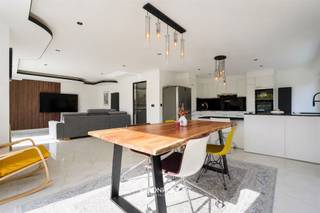 <p><span>Deze ruime en moderne woning combineert hedendaags wooncomfort met een stijlvolle afwerking en een doordachte indeling. Met een woonoppervlakte van 314 m² op een perceel van 955 m² biedt de woning bijzonder veel ruimte. Dankzij de zes slaapkamers, de lichtrijke leefruimtes en de aangename buitenruimte is dit een ideale gezinswoning.</span></p><p> </p><hr /><p><span>Via de inkomhal bereikt u de ruime leefruimte. De open indeling zorgt voor een aangenaam ruimtegevoel en biedt voldoende plaats voor een gezellige zit- en eethoek. Grote raampartijen zorgen voor een mooie natuurlijke lichtinval en creëren een fijne verbinding met de tuin.</span></p><p><span>Aansluitend bevindt zich de moderne open keuken, waar functionaliteit en uitstraling mooi samenkomen. De witte keukenfronten in combinatie met het donkere werkblad zorgen voor een eigentijdse uitstraling. Dankzij de ruime werkbladen en twee ovens beschikt u hier over alle comfort om dagelijks te koken of uitgebreid te tafelen. De bar vormt een gezellige plek om samen te komen met familie en vrienden.</span></p><p> </p><hr /><p><span>De woning beschikt over zes volwaardige slaapkamers, waardoor er naast slaapvertrekken ook mogelijkheden zijn voor een bureau, hobbyruimte, dressing of speelkamer. De kamers zijn ruim en lichtrijk en werden verzorgd afgewerkt. Een van de slaapkamers valt op door de warme houten wandafwerking, die zorgt voor een karaktervolle uitstraling.</span></p><p><span>Ook de badkamer werd modern ingericht en beschikt over een dubbele wastafel, zwarte inbouwkranen en een ruime inloopdouche met glazen wand. De tegels in marmereffect en sfeerverlichting zorgen voor een aangename uitstraling.</span></p><p> </p><hr /><p><span>Buiten geniet u van een ruim terras en een volledig omheinde tuin. Het terras vormt een fijne plek om te ontspannen of gezellig te tafelen, terwijl de groene tuin de nodige privacy biedt. Dankzij de ruime oppervlakte zijn er verschillende mogelijkheden om de buitenruimte naar eigen wens in te richten.</span></p><p><span>De combinatie van de ruime woonoppervlakte, zes slaapkamers, moderne afwerking, het royale perceel en de aangename tuin maakt deze woning bijzonder geschikt voor gezinnen die op zoek zijn naar ruimte en comfort.</span></p><p><span>Plan uw bezoek eenvoudig online, telefonisch via 09 310 77 07 of mail naar </span><span>info@woonhoekvastgoed.be</span><span>.</span></p>