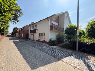 <p>Gelegen in een aangename en rustige omgeving in Geluwe bevindt zich deze ruime halfopen gezinswoning met garage, praktische uitweg langs de zijkant en een gezellige tuin. Dankzij de vier slaapkamers, de lichtrijke leefruimte en de praktische indeling is deze woning ideaal voor gezinnen die op zoek zijn naar ruimte en comfort.</p>
<p><strong>Indeling:</strong> Gelijkvloers: inkomhal, apart toilet, ruime leefruimte, halfopen keuken met zicht op de tuin, berging/wasplaats, garage en kelder. Eerste verdieping: nachthal, 4 slaapkamers, waarvan één met een balkon, en een badkamer met toilet. Er is ook een zolder aanwezig, die extra opbergmogelijkheden biedt.</p>
<p><strong>Troeven:</strong></p>
<ul><li>Halfopen bebouwing</li><li>Garage met uitweg langs de zijkant</li><li>4 volwaardige slaapkamers</li><li>2 toiletten</li><li>Lichtrijke leefruimte met zicht op de tuin</li><li>Praktische berging/wasplaats</li><li>Kelder en zolder aanwezig</li><li>Mooie, gezellige tuin</li></ul>