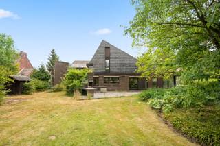 Deze bijzonder knappe en originele woning geniet van een uitzonderlijke ligging in het charmante Hoegaarden, een gemeente die bekendstaat om haar groene karakter, aangename woonomgeving en uitstekende bereikbaarheid. De woning werd met veel aandacht voor architectuur, ruimte en licht ontworpen en biedt een unieke woonbeleving voor wie op zoek is naar een eigendom met karakter.<br /><br />De grote, mooie aangelegde tuin vormt een absolute blikvanger en biedt een uitzonderlijk weids uitzicht dat zorgt voor een gevoel van rust, ruimte en privacy. Een zeldzame troef die deze woning een bijzonder exclusieve uitstraling geeft.<br /><br />Binnen ontdekt u royale leefruimtes met onder meer een ruime eetkamer en een gezellige zitkamer, ideaal voor sfeervolle familiemomenten of het ontvangen van gasten. De woning beschikt bovendien over vijf volwaardige slaapkamers, waardoor ze perfect geschikt is voor een groot gezin of voor wie extra ruimte wenst.<br /><br />Een bijzondere meerwaarde is het volledig afgescheiden gedeelte voor een vrij beroep of zelfstandige activiteit. Dit omvat een aparte inkomhal met wachtkamer, een bureel en een praktijkruimte, waardoor wonen en werken op een professionele en comfortabele manier gecombineerd kunnen worden.<br /><br />De woning dient opgefrist/gerenoveerd te worden om ze volledig af te stemmen op de hedendaagse woonnormen van 2026. Dankzij haar uitzonderlijke architectuur, de royale volumes, de unieke tuin en de veelzijdige indeling biedt deze eigendom een bijzonder potentieel om uit te groeien tot een hedendaagse droomwoning met behoud van haar originele karakter en uitstraling.<br /><br />Een zeldzame kans voor wie op zoek is naar een karaktervolle woning op een prachtige locatie in Hoegaarden.