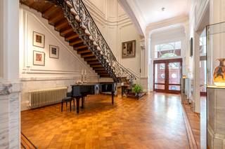 <p>Gelegen aan de befaamde Jan van Rijswijcklaan bevindt zich deze authentieke meesterwoning met conciergerie en garage.<br /><br />Uitzonderlijk brede gevel in Beaux-Art-stijl uit 1910. <br />De statige inkomhal met vestiaire leidt naar de verscheidene vertrekken van de woning.<br />Het ontvangstsalon en zitkamer heeft rijkelijk versierde hoge plafonds en origineel schrijnwerk. Vervolgens een salon met formele eetkamer in de erker met uitzicht op de tuin. De keuken is voorzien van de gebruikelijke toestellen.<br />De eerste verdieping is ingericht met royale masterslaapkamer en ensuite zéér comfortabele Italiaanse badkamer. Het bureau met ingemaakt kastenwerk kan tevens functioneren als bibliotheek.<br />De tweede verdieping, ook bereikbaar per lift, herbergt twee extra slaapkamers met eigen badkamer. Een derde kamer is momenteel speelkamer. Er is tevens een kitchenette voorzien.<br />De sous-terrain biedt een ontspanningsruimte met bar, fitnessruimte en wijnkelder. De technische berging en wasplaats bevinden zich eveneens op deze verdieping. <br />Via de tuin met verschillende terrassen heeft u toegang tot de achterliggende garage.</p>