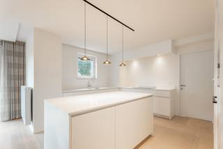 Schitterend gelijkvloers appartement, volledig afgewerkt en nooit bewoond. Hier stapt u binnen in een gloednieuwe, tijdloze leefomgeving van topkwaliteit. Domoticasysteem, op maat gemaakt meubilair en een terras met zicht op de vijver maken dit appartement bijzonder.<br /><br />De inkomhal leidt naar een lichtrijke living met rondom raampartijen, aansluitend op de geïnstalleerde keuken met composiet werkblad en kookeiland. Twee ruime slaapkamers, waarvan één met en-suite badkamer (dubbele wastafel, inloopdouche, apart toilet) en een tweede met eigen wastafel en douche. Een derde kamer is vandaag ingericht als strijkkamer/bureau, maar evengoed bruikbaar als dressing of kinderkamer.<br /><br />Via de living stapt u rechtstreeks het terras op, met zicht op de vijver en het groene domein. Een ondergrondse, afgesloten garagebox met ruimte voor een grote wagen en extra stockage maakt het plaatje compleet. Deze is bij te kopen voor € 40.000<br /><br />Een gloednieuw appartement met deze afwerking en ligging is zeldzaam. Plan snel uw bezoek.<br /><br />Referentie: YP/26069/TK