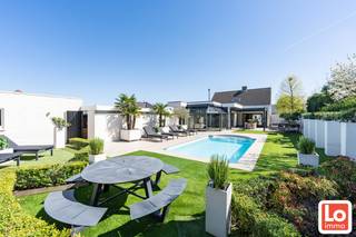 Op een rustige locatie bevindt zich deze ruime, prachtig afgewerkte en instapklare villa.<br /><br />Via de inkomhal komt u in de leefruimte, waar u meteen aangenaam wordt verrast door de overvloedige lichtinval dankzij de grote glaspartijen.<br />Links bevindt zich een ruimte die is ingericht als bureau, in rechtstreeks contact met de keuken. De grote, moderne leef-keuken vormt het centrale hart van de woning en is uitgerust met een eiland, ideaal om zowel aan te tafelen als te ontbijten.<br />Aansluitend aan de keuken vindt u een aparte berging en wasplaats, die bijzonder functioneel zijn ingericht. Verder in de woning is er een aparte eetruimte met aansluitend een zitgedeelte, badend in het licht en met een mooi zicht op de tuin. Vanuit de zithoek geniet u ’s avonds zowel van de gezellige houtkachel als van het uitzicht op het zwembad en de perfect aangelegde tuin.<br />Op het gelijkvloers bevindt zich tevens een slaapkamer, die ook perfect kan dienen als bureau of multifunctionele ruimte.<br /><br />Op de verdieping zijn er drie slaapkamers, waaronder een master slaapkamer met ingemaakte kasten en twee kinderkamers. De badkamer is uitgerust met dubbel lavabomeubel, toilet en inloopdouche.<br /><br />Buiten vormt het terras met aluminium overkapping met screens een absolute meerwaarde, waardoor u gedurende vele maanden van de tuin kunt genieten. Het zwembad en de prachtige poolhouse met sanitair en sauna maken deze eigendom helemaal compleet.<br />Rechts van de woning bereikt u via de carport de vrijstaande garage.<br /><br />De woning is bovendien uitgerust met zonnepanelen incl. certificaten. De woning is elektrisch verwarmd en kan mits installatie van een lucht/lucht warmtepomp onmiddellijk een EPC label B verkrijgen!<br /><br />Kortom: een perfect onderhouden en ruime woning met alle comfort, gelegen in het gegeerde Lochristi.<br /><br />Wilt u deze prachtige woning bezoeken op zaterdag 13 Juni enkel via deze link: https://calendly.com/loimmo/bezoekmoment-dahlialaan6<br /> 