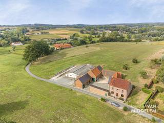 <strong>Bent u op zoek naar een eigendom met karakter, ruimte en potentieel? Dan is deze te renoveren hoeve op een prachtig geheel van +/- 8ha35a zeker iets voor u!</strong><br /><strong>De hoeve ligt in landschappelijk waardevol agrarisch gebied, weg van alle drukte en met een prachtig zicht over de aanpalende velden.</strong><br /><br />Een bijzondere troef zijn de omvangrijke, grotendeels aaneensluitende pachtvrije gronden, die samen met de hoeve en de verschillende bijgebouwen één mooi geheel vormen. Dit biedt heel wat mogelijkheden voor een agrarische of andere landelijke invulling. Ook fruit- of wijnbouw kan, gelet op de ligging in het Pajottenland, een interessante piste zijn.<br /><br />De woning (± 285 m² bruto) is als volgt ingedeeld:<br /><br />- Gelijkvloers: inkomhal, leefruimte, eetplaats, keuken, badkamer en wc;<br />- 1ste verdieping: 4 slaapkamers en bureau;<br />- Zolder: bereikbaar via vaste trap en mogelijk verder in te richten;<br />- Kelder<br /><br />Daarnaast beschikt de eigendom over verschillende grote bijgebouwen, waaronder schuren, stallen en bergingen.<br /><br />De woning is momenteel vergund als HOEVE met uitsluitend landbouwfunctie. Een functiewijziging naar eengezinswoning kan mogelijk zijn, mits het verkrijgen van de nodige vergunningen en het voldoen aan de geldende voorwaarden.<br /><br />Hoewel de woning steeds goed onderhouden werd, dient ze volledig gerenoveerd te worden om aan de huidige normen te voldoen. De renovatieplicht is van toepassing.<br /><br />Kortom, een bijzondere eigendom met tal van mogelijkheden op een prachtige landelijke ligging in het Pajottenland.<br /><br />EPC: 1029 kWh/m².jaar - Label F (UC: 3944502)<br />± 8ha35a – PACHTVRIJ<br />Vrij bij akte.