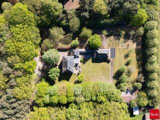Wie op zoek is naar ruimte, rust en veelzijdigheid, voelt zich hier meteen thuis. Deze uitzonderlijke vrijstaande woning is gelegen op een prachtig perceel van maar liefst 8.392 m² en combineert royale volumes met privacy, comfort en een uniek groen kader.<br /><br />De woning wordt omgeven door een schitterende, volwassen en perfect georiënteerde zuidgerichte tuin, waar je in alle rust geniet van zon, natuur en een weids uitzicht op het omliggende groen. De ruime oprit en garage zorgen bovendien voor optimaal praktisch comfort en voldoende parkeergelegenheid.<br /><br />Binnen verwelkomt de woning je met bijzonder royale leefvolumes en een doordachte indeling. <br />De woning beschikt over 4 bijzonder ruime slaapkamers, elk met veel lichtinval en tal van indelingsmogelijkheden. De badkamer is volledig uitgerust en biedt alle comfort met zowel een ligbad als een douche.<br /><br />Een extra troef is de ruime zolderverdieping, bereikbaar via een vaste trap. Deze polyvalente ruimte biedt nog tal van mogelijkheden en kan perfect ingericht worden als extra slaapkamers, hobbyruimte, bureau of ontspanningsruimte.<br /><br />De inpandige dubbele garage heeft nog een bijkomende zolder die ook nog volledig ingericht kan worden. <br /><br />Naast het hoofdgebouw is er nog een bijgebouw dat volledig voorzien is van keuken en badkamer en mogelijkheid bied voor uitbreiding van 1 naar 3 slaapkamers. <br /><br />Dit eigendom biedt een uitzonderlijke flexibiliteit en is ze uitermate geschikt voor cohousing, kangoeroewonen, een praktijk aan huis of het comfortabel samenwonen van meerdere generaties.<br /><br />Daarnaast biedt deze woning ook energetisch nog interessante opportuniteiten: met een beperkte investering kan het EPC aanzienlijk verbeterd worden. Bij de plaatsing van een warmtepomp en het verwijderen van de houtkachel kan de EPC-score stijgen naar begin label B, wat een mooie meerwaarde betekent voor de toekomstige eigenaar.<br /><br />Contacteer Vincent voor een bezoek ter plaatse via 0475 21 00 86 of Vincent@reds.be.