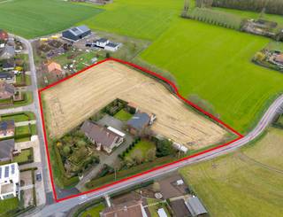 Ruime woning met loods en landbouwgrond op groene locatie nabij Waregem.<br /><br />Op een rustige en landelijke ligging in Zulte bevindt zich deze ruime open bebouwing met bijhorende landbouwgrond. De woning is omgeven door groen en ligt toch op korte afstand van Waregem, waardoor u geniet van rust én een vlotte bereikbaarheid.<br /><br />Via de oprijlaan bereikt u de woning. Vooraan is er een ruime voortuin met voldoende parkeergelegenheid. U komt binnen via de centrale inkomhal die toegang geeft tot de verschillende ruimtes.<br /><br />Aan de rechterzijde bevindt zich de leefruimte met grote raampartijen en een mooi zicht op de tuin. De houtkachel zorgt voor extra gezelligheid in de winter, terwijl de veranda een aangename plek is om van het licht en de zon te genieten.<br /><br />Aansluitend ligt de keuken, uitgerust met toestellen en met zicht op de tuin. Vanuit de keuken heeft u toegang tot de kelder, een apart toilet en de achterdeur.<br /><br />Verder in de gang bevinden zich drie slaapkamers, een tweede toilet en een badkamer met dubbele lavabo, ligbad en douche. Vanuit de hal bereikt u ook de ruime garage met twee geautomatiseerde poorten, waar naast parkeren ook plaats is voor wasruimte en extra berging.<br /><br />Op de eerste verdieping komt u in een ruime nachthal met toegang tot een vierde slaapkamer, een tweede badkamer met lavabo, toilet en inloopdouche, een vijfde kamer en een zeer ruime zolder die nog verder kan ingericht worden.<br /><br />Via de achterdeur komt u in de tuin met een overdekt terras en een ruime groene buitenruimte. Daarnaast beschikt het perceel over een loods van 120 m² en meerdere bijgebouwen.<br /><br />De verkoop omvat drie percelen landbouwgrond: B503/00D, B504/00 en B500/00A.<br /><br />Bent u op zoek naar een ruime woning met landbouwgrond op een rustige ligging? Dan is dit pand zeker een bezoek waard. Plan vandaag nog uw bezoek in.