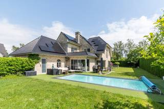 Deze exclusieve, vrijstaande villa in landelijke stijl in Wemmel straalt pure klasse uit. Met een royale bewoonbare oppervlakte van 526 m² en een superieure afwerkingsgraad geniet u hier van uitzonderlijk wooncomfort. De zandkleurige gevel combineert harmonieus met charmante dakkapellen en een monumentale glaspartij bij de inkom. De woning is energie-efficiënt uitgerust met zonnepanelen en een hoogwaardig alarmsysteem.<br /><br />De villa ligt op een discreet perceel, volledig aan het oog onttrokken via een lange privé-inrit. Dit garandeert honderd procent privacy en sereniteit, terwijl scholen, openbaar vervoer en de Brusselse Ring (R0) vlakbij zijn.<br /><br />Binnen opent de inkomhal in een spectaculaire vide met een marmeren trappartij. De centrale leefruimte ademt licht dankzij kamerhoge schuiframen naar de tuin. De living beschikt over een formele eethoek, een zithoek met maatwerkkasten en een sfeervol tweede salon met gashaard. Daarnaast is er een onafhankelijke praktijk- of kantoorruimte op het gelijkvloers.<br /><br />De high-end leefkeuken met werkeiland en premium Miele-apparatuur sluit naadloos aan op het terras. Op de verdieping biedt de mezzanine toegang tot vier grote slaapkamers met ingebouwde kasten en drie stijlvolle, moderne badkamers. De master suite beschikt over een eigen dakterras.<br /><br />De prachtig aangelegde tuin is omzoomd door hoge hagen en beschikt over een strak buitenzwembad met hardhouten zonneterrassen. Aan de voorzijde biedt de oprit plaats voor een tal van wagens.<br /><br />Bestuursmaatregelen in het maatregelenregister: nee