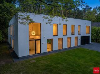 <p>Een villa die fluistert met het bos — overal waar u kijkt, de natuur.</p>
<p>In het hart van het gegeerde Koningshof in Schoten, discreet gelegen in een doodlopende straat, bevindt zich deze uitzonderlijke villa. Een plek waar stilte, privacy en natuur de hoofdrol spelen, op wandelafstand van het centrum, scholen en sportvoorzieningen. Hier woont u omringd door groen, zonder in te boeten aan bereikbaarheid.<br />De woning is volledig georiënteerd naar de tuin en het fenomenale uitzicht op het omliggende groen. Vanuit elke kamer kijkt u op een tapijt van dennenbomen. Het gevoel om in de natuur te wonen is hier geen belofte — het is uw dagelijkse realiteit. Rust, privacy en ruimte vloeien hier naadloos samen.</p>
<p><strong>Gelijkvloers- elegantie en leefkwaliteit in harmonie<br /></strong>Bij het betreden van de villa wordt u verwelkomd in een indrukwekkende inkomhal met hoge plafonds, ingebouwde vestiairekasten en gastentoilet — een eerste indruk die onmiddellijk de toon zet.<br />De leefruimte ademt warmte en verfijning, met een sfeervolle zithoek voorzien van gashaard, een stijlvolle bar en maatwerkkasten die perfect opgaan in het geheel. Grote raampartijen met adembenemend uitzicht op de bos, verbinden interieur en natuur naadloos met elkaar en geven rechtstreeks toegang tot het terras en de tuin.<br />De keuken vormt het absolute hart van de woning en is uitgevoerd met hoogwaardige materialen en de meest moderne, geïntegreerde toestellen. Aansluitend bevindt zich een elegante eetruimte weeral met panoramisch zicht op het groen.<br />Op subtiele wijze werd in de leefruimte een bureauruimte met ingemaakte kasten geïntegreerd, ideaal voor thuiswerk. Daarnaast is er een polyvalente ruimte die kan worden ingericht als speelkamer of extra kantoor.<br />Het zonovergoten terras sluit harmonieus aan op de leefruimtes en vormt een natuurlijke overgang naar de tuin — de perfecte plek om in alle rust te genieten van de natuur. Verder beschikt de woning over een dubbele garage en een kelder met kruipruimte onder het volledige gebouw.</p>
<p><strong>Eerste verdieping – een private suite op uitzonderlijk niveau<br /></strong>Via de elegante trap bereikt u de eerste verdieping, waar een overloop in visgraatparket toegang geeft tot vier slaapkamers.<br />De master suite van liefst ca. 100 m² vormt een private wereld op zich. Een royale slaapkamer vloeit over in een op maat gemaakte dressing en leidt naar een luxueuze badkamer van uitzonderlijk niveau, uitgerust met vrijstaand ligbad, dubbele regendouche en hoogwaardig kraanwerk. Het panoramische uitzicht op de omliggende dennenbossen maakt deze ruimte werkelijk uniek.<br />De drie overige slaapkamers (ca. 22 m², 18 m² en 15 m²) zijn eveneens afgewerkt met maatwerkkasten en genieten allen van een prachtig zicht op het groen.<br />Ook de kinderen beschikken over een stijlvolle badkamer met inloopdouche, dubbele lavabo en toilet. Bovendien bestaat de mogelijkheid om een derde badkamer te creëren.<br /><br /><strong>TECHNOLOGIE & DUURZAAMHEID <br /></strong>Het geheel is afgewerkt met de <strong>finest materialen</strong> en uitgerust met de <strong>meest geavanceerde technieken:</strong> zonnepanelen met thuisbatterij, geothermische warmtepomp, ventilatiesysteem type D, vloerverwarming (verwarmen én koelen), domotica, alarmsysteem en camerabewaking. Kortom — een uiterst energiezuinige en toekomstgerichte thuisbasis met EPC-label A+.</p>
<p>Deze villa is geen gewone woning, maar een totaalbeleving waar privacy, ruimte en luxe harmonieus samenkomen in een uitzonderlijk groene en discrete setting.<br /><br />Voor meer informatie of een bezichtiging van deze uitzonderlijk villa neem gerust contact met Stephanie of Sigalit via stephanie@reds.be of sigalit@reds.be.</p>
<p><br /><br /></p>