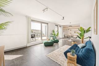 Deze instapklare penthouse is gelegen in de Lange Sint-Annastraat, een karaktervolle straat in het hart van Antwerpen, op het kruispunt van het Eilandje, de universiteitswijk en het historische centrum. Stijlvolle winkels, kwalitatieve horeca en culturele hotspots bevinden zich op wandelafstand, net als de Meir, Groenplaats en Grote Markt. Dankzij deze centrale ligging geniet u van het bruisende stadsleven, terwijl u bovenaan het gebouw in alle rust thuiskomt. Zowel openbaar vervoer als belangrijke invalswegen zijn vlot bereikbaar.<br /><br />Het appartement bevindt zich op de bovenste verdieping van een recente en verzorgde residentie. De lichtrijke leefruimte vormt het hart van het appartement en geeft via grote raampartijen toegang tot twee ruime zonneterrassen aan weerszijden. Dit zorgt de hele dag door voor overvloedig natuurlijk licht en een aangenaam panoramisch uitzicht over de stad. Aansluitend aan de leefruimte bevindt zich een aparte bureauruimte, ideaal als thuiswerkplek of in te richten als derde slaapkamer.<br /><br />De keuken is volledig uitgerust met kwalitatieve toestellen en een ruim werkblad, perfect voor wie graag kookt en gasten ontvangt. Verder beschikt het appartement over twee ruime slaapkamers, een modern afgewerkte badkamer met ligbad, inloopdouche en dubbel lavabomeubel, een apart gastentoilet en een praktische (was) berging. <br />Een privatieve kelderberging en gemeenschappelijke fietsenberging zijn inbegrepen. De aankoop van een ondergrondse autostaanplaats is mogelijk.