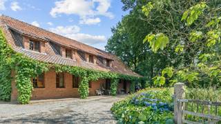 TESSENDERLO - Aan het einde van een doodlopende weg, grenzend aan de prachtige natuur van het Averbode Bos, ligt deze karaktervolle hoeve die absolute privacy en rust garandeert. Een unieke eigendom waar authenticiteit, comfort en landelijke charme samenkomen.<br /><br />De woning onderging in de jaren ’90 een grondige totaalrenovatie met oog voor hoogwaardige materialen en behoud van het originele karakter.<br /><br />Bij het binnenkomen wordt u verwelkomd in een ruime inkomhal die toegang biedt tot een bureel. Daarachter ontvouwt zich een imposante leefruimte met een plafondhoogte van maar liefst vijf meter. De landelijke keuken nodigt uit om gezellig aan te schuiven aan de boerentafel, terwijl aanpalende bergingen goed zijn voor praktisch en technische zaken.<br /><br />Op de verdieping vindt u drie slaapkamers en een badkamer aan de ene zijde, en een vierde kamer met slaapzolder en eigen terras aan de andere zijde – perfect voor een tiener, gasten of een creatieve invulling.<br /><br />Naast de hoofdwoning beschikt de hoeve over drie schuren, waaronder één met vier paardenstallen en hooizolder. Deze geven rechtstreeks toegang tot het uitgestrekte, aansluitende weiland: een droom voor paardenliefhebbers of wie houdt van buitenleven.<br /><br />Bent u op zoek naar een authentieke hoeve waar privacy, ruimte en natuurbeleving centraal staan ? Dan is dit een unieke kans om uw droom waar te maken.<br /><br />Contacteer ons op 053/60 65 66 voor het inplannen van een plaatsbezoek.