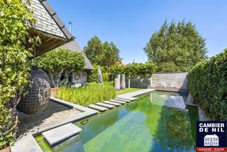 Architectenwoning - Zeer ruime villa met buitengewone voorzieningen voor vrij beroep. Genietend van prachtige, zuidgerichte leeftuin. Topligging in rustige residentiële wijk op enkele minuten van Het Zoute.
Indeling: ruime inkomhall met zeer hoge vide, wachtzaal en toilet, praktijkruimte en trap naar fitness op eerste verdieping, toegang naar spacieuze woonkamer met eetplaats en aparte keuken beiden uitgevend op de tuin, grote berging met toegang tot zolder dienst doende als tv-room, eerste verdieping: drie slaapkamers, één badkamer en zeer ruime, lichtrijke fitness. Op tweede verdieping royale slaapkamer met grote dressing en badkamer. Tuin met zwemvijver en jacuzzi, mooi aangelegde terrassen én petanquebaan. Oprit voor 3 wagens, carport en fietsenstalling met bijkomende binnenstaanplaats voor wagen. Uitzonderlijke parkeermogelijkheid voor gasten langs de woning. Mooi dossier!
(EPC 191 - UC 20200628-0002287316-RES-1)